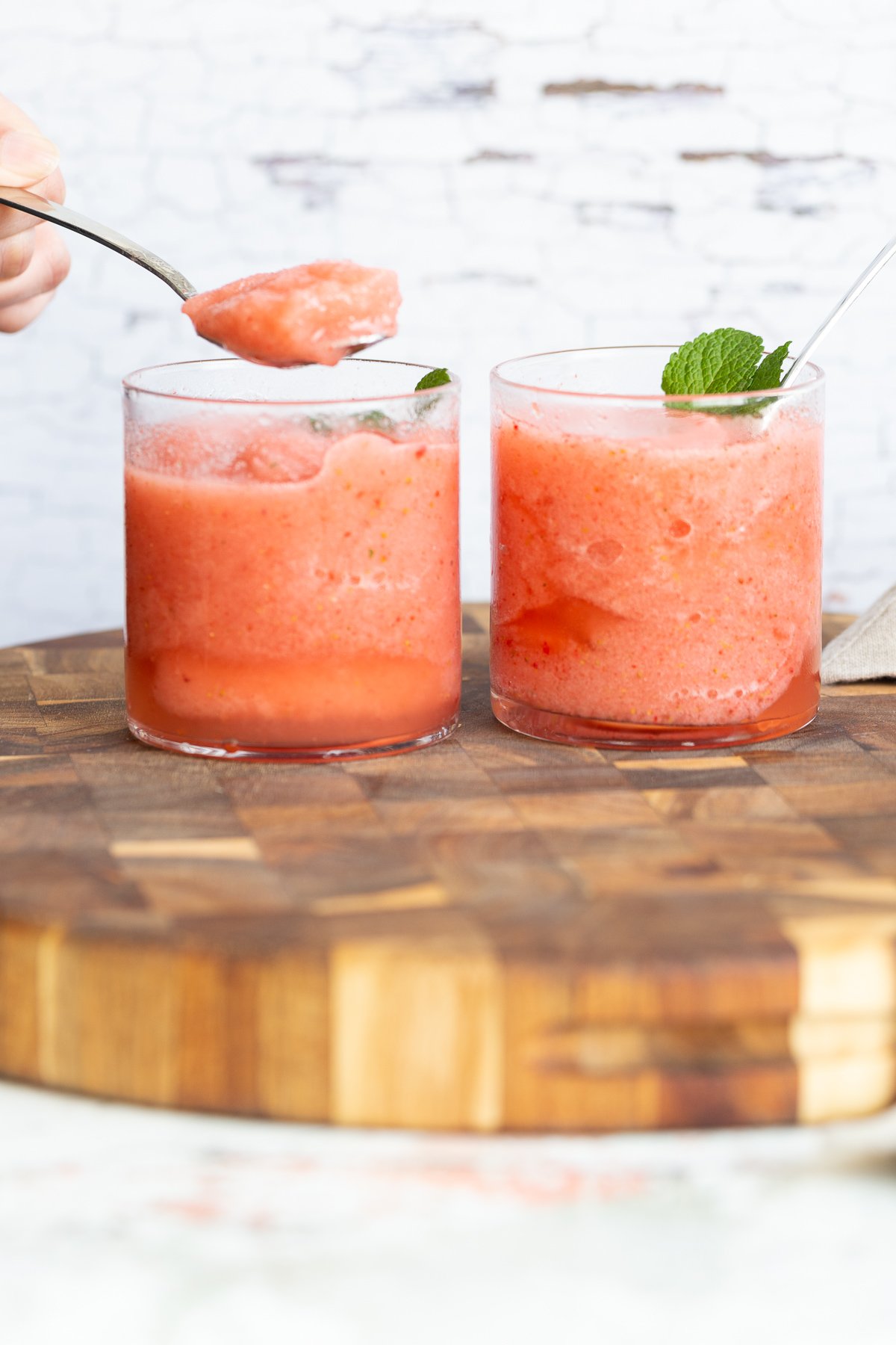 lemonade slushie two glasses with homemade vegan strawberry lemonade slushies on a wooden board