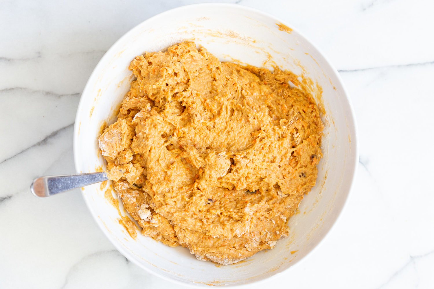 vegan carrot bread  stiff vegan carrot bread batter in a mixing bowl with a spoon