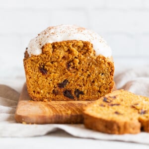 a loaf of vegan pumpkin carrot bread sliced on a chopping board