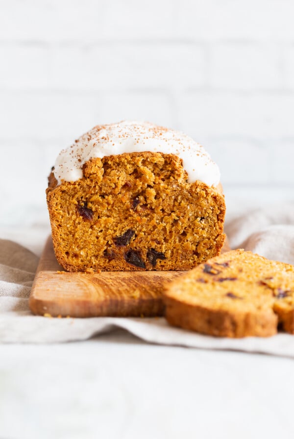 a loaf of vegan pumpkin carrot bread sliced on a chopping board