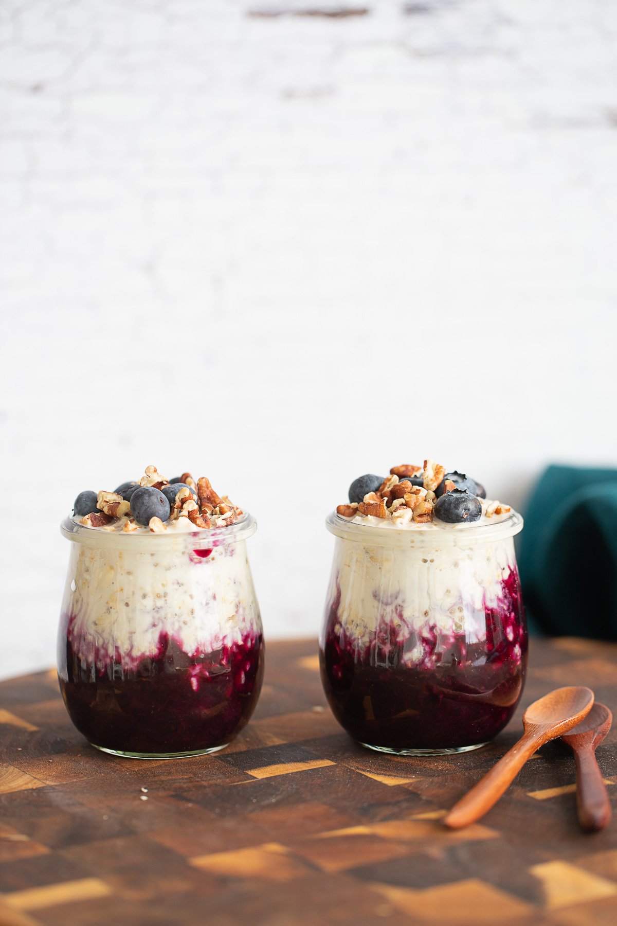 blueberry overnight oats  side view of two jars of blueberry overnight oats on a wooden board