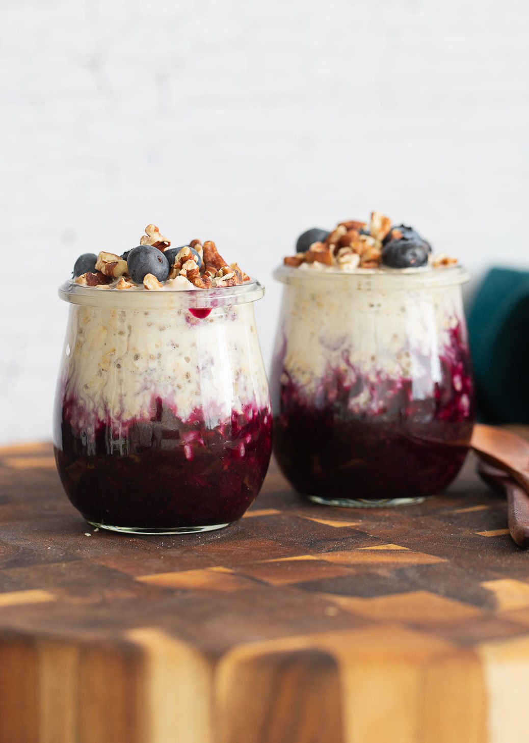 blueberry overnight oats blueberry muffin overnight oats in small mason jars topped with chopped pecans and blueberries