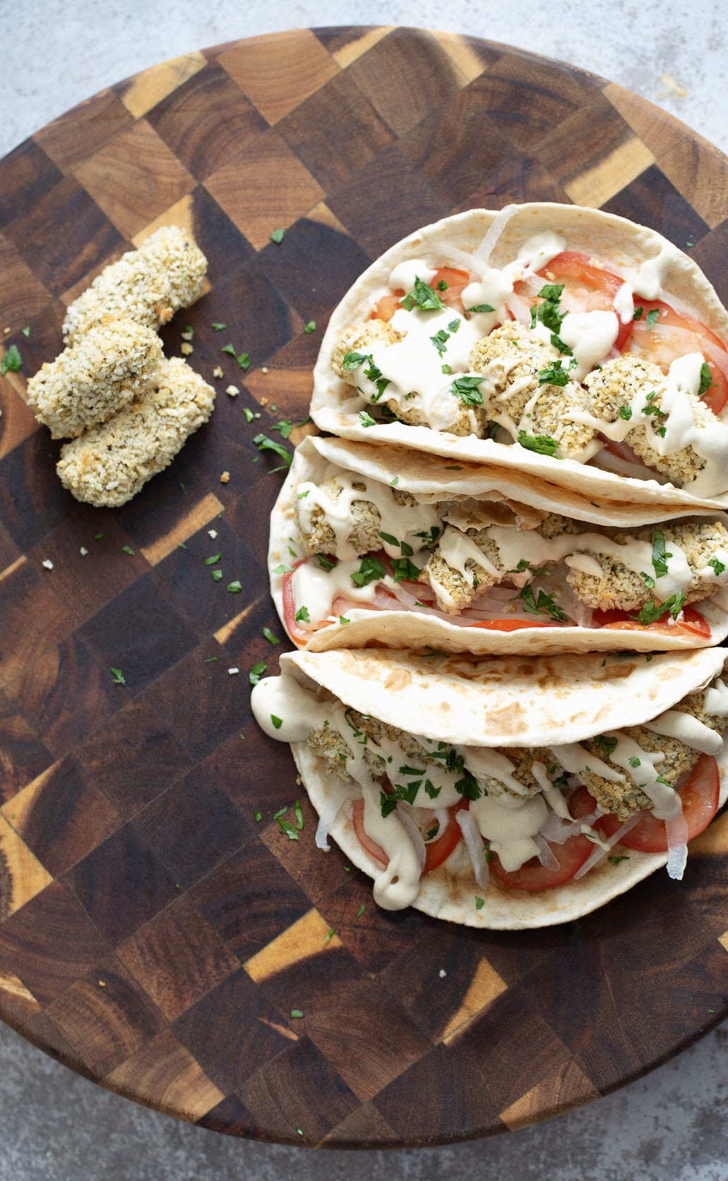 three vegan wraps filled with vegan chickpea quinoa croquettes and drizzled with tahini sauce