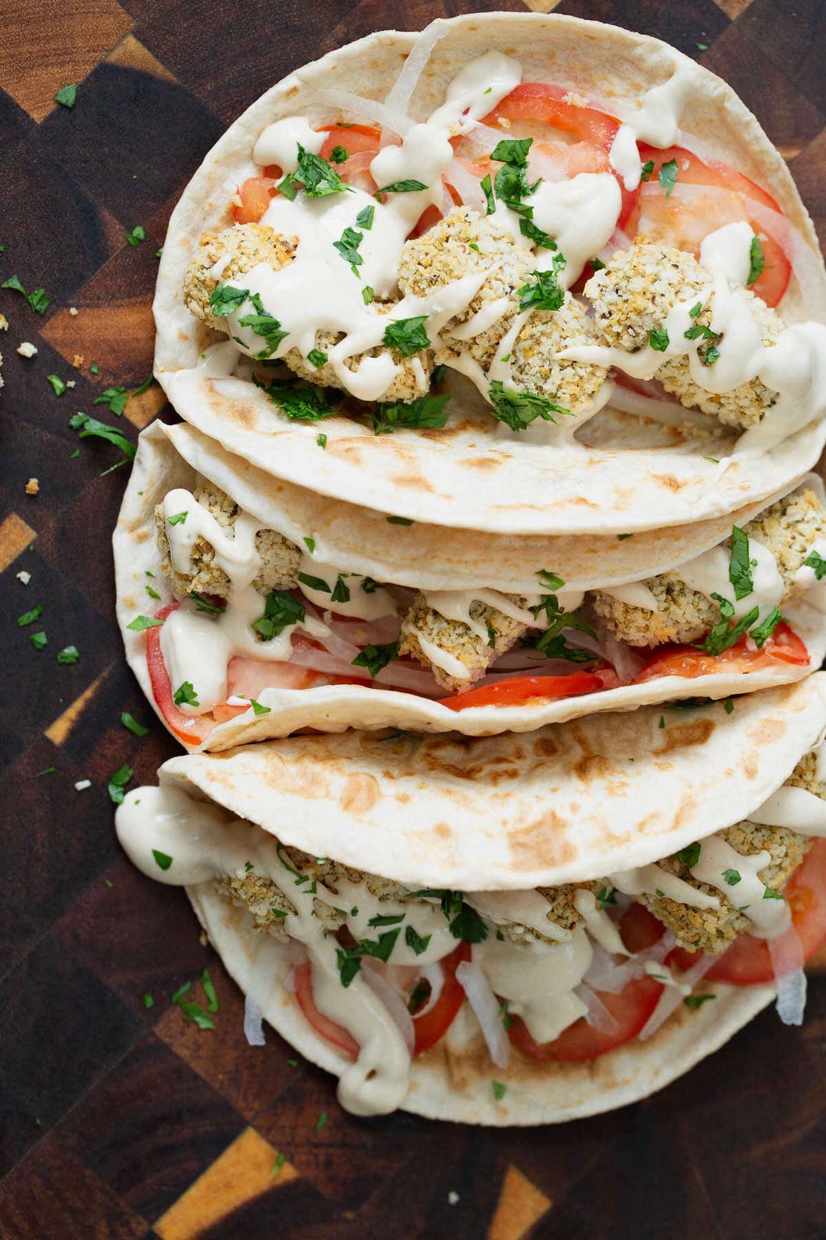 three vegan wraps filled with vegan chickpea quinoa croquettes and drizzled with tahini sauce