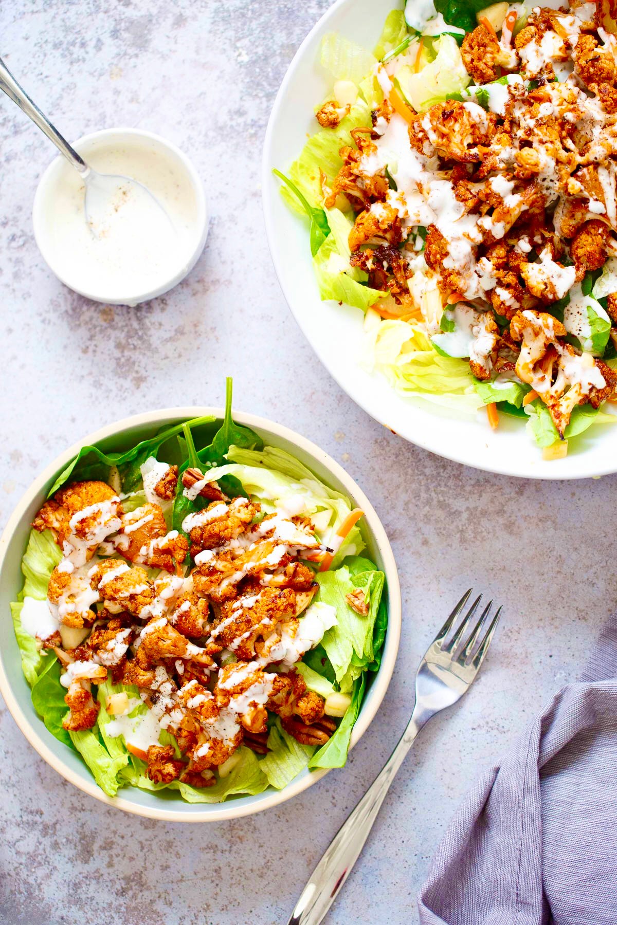 overhead shot of a salad bowl topped with bbq roasted cauliflower and vegan ranch dressing