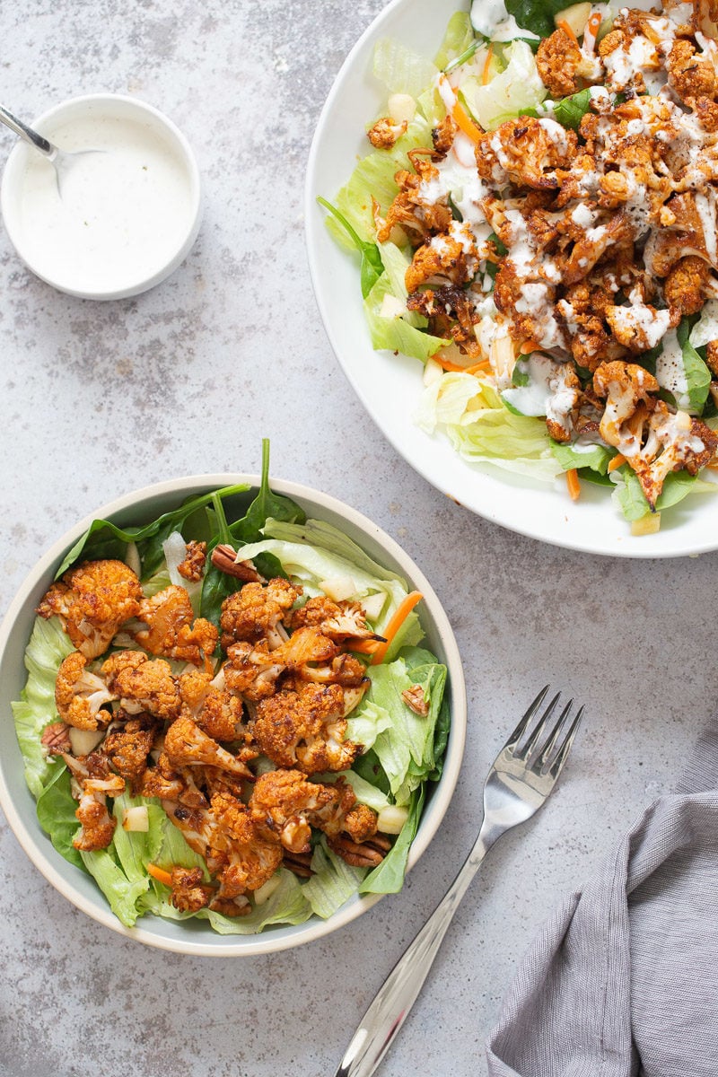 overhead shot of a spicy bbq roasted cauliflower salad bowl in a white bowl drizzled with Vegan Ranch Dressing ” data-jpibfi-post-excerpt=