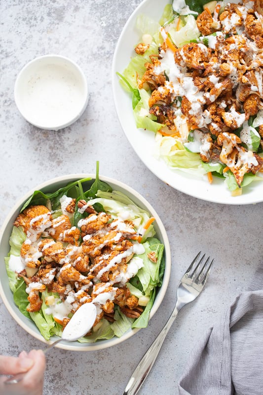 cauliflower salad vegan bbq roasted cauliflower salad bowl being drizzled with vegan Ranch Dressing