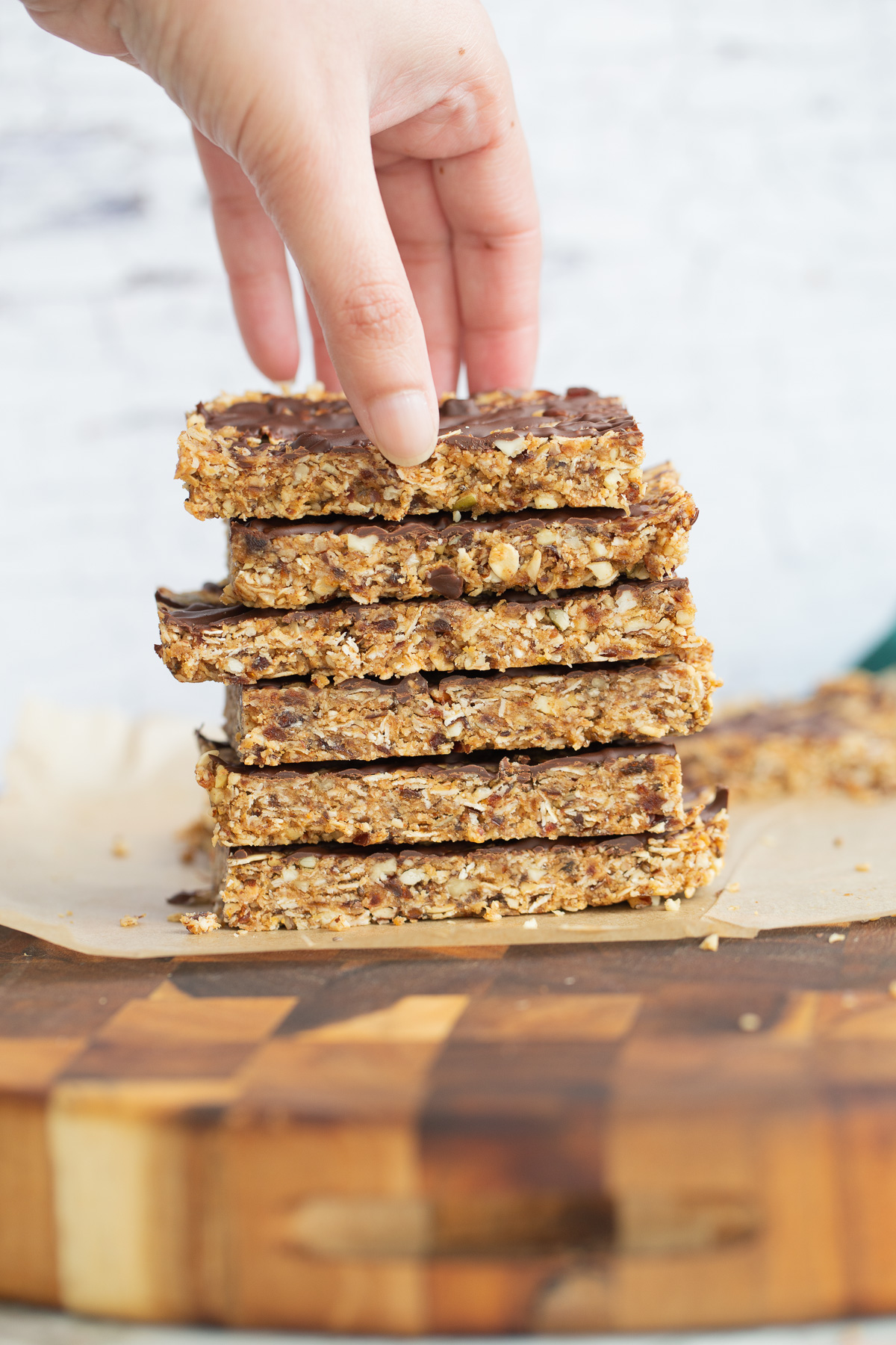 vegan date bars  a hand reaching for a vegan date bar on top of a stack of vegan snack bars