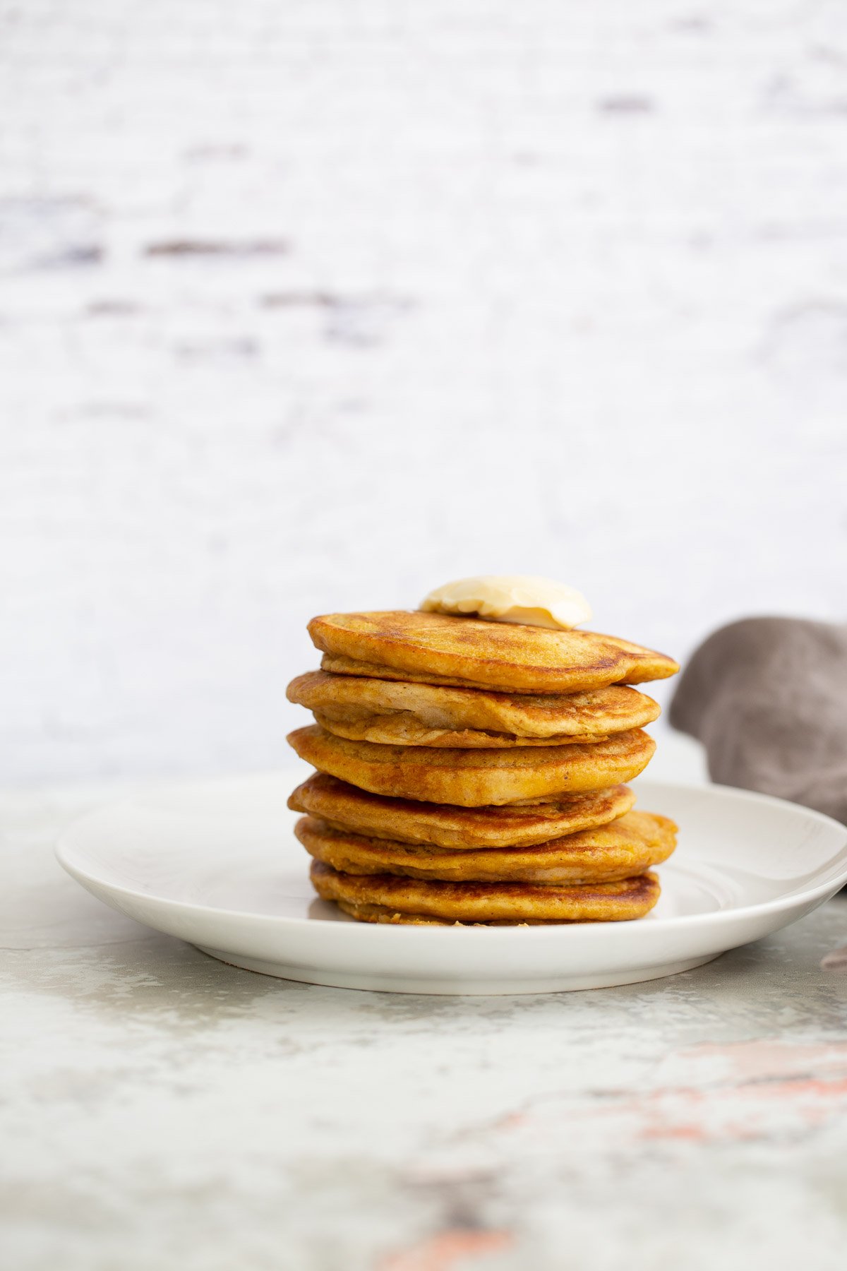 vegan pumpkin pancakes a stack of vegan pumpkin pancakes against a white brick wall