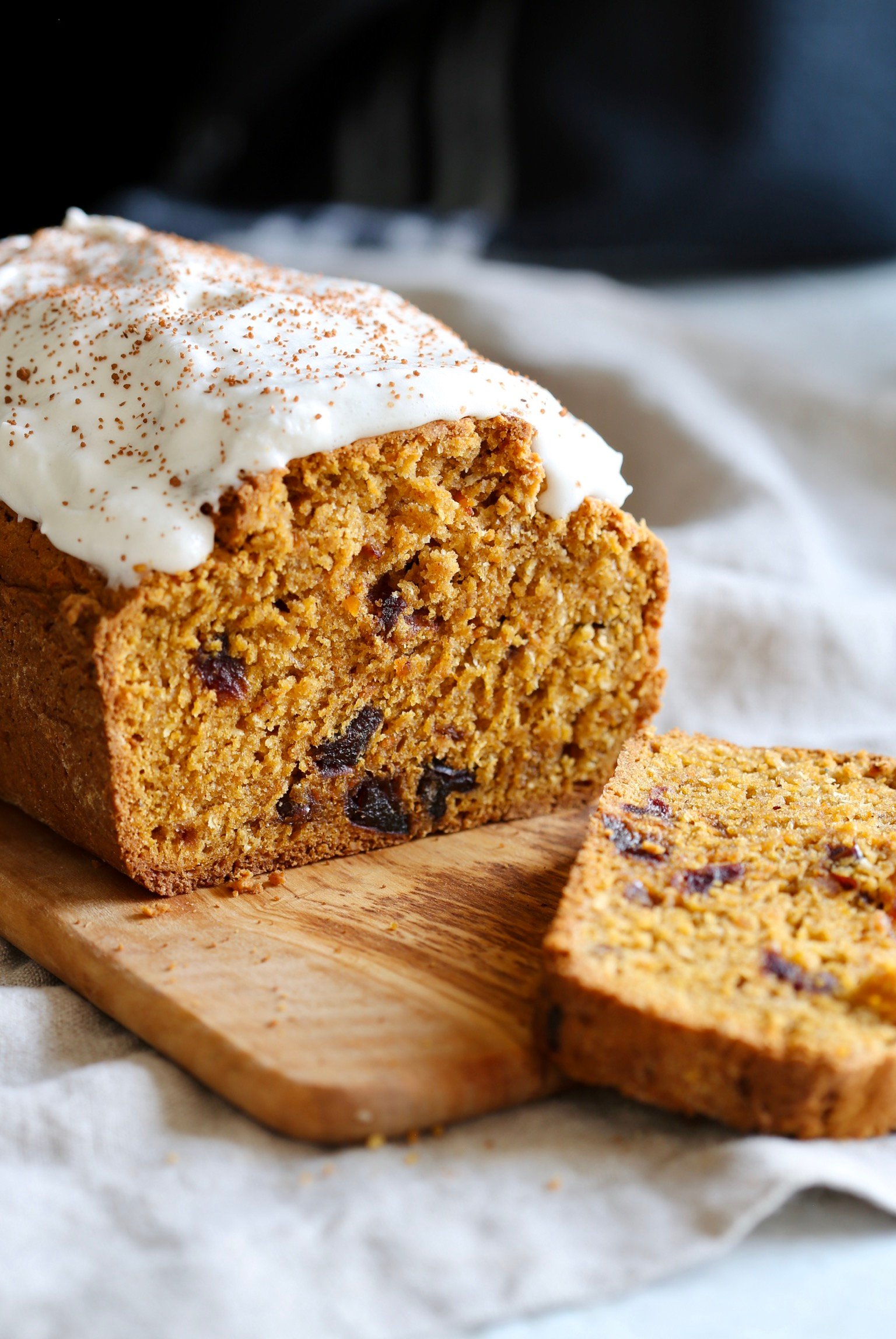 a sliced loaf of vegan pumpkin carrot bread on a wooden cutting board