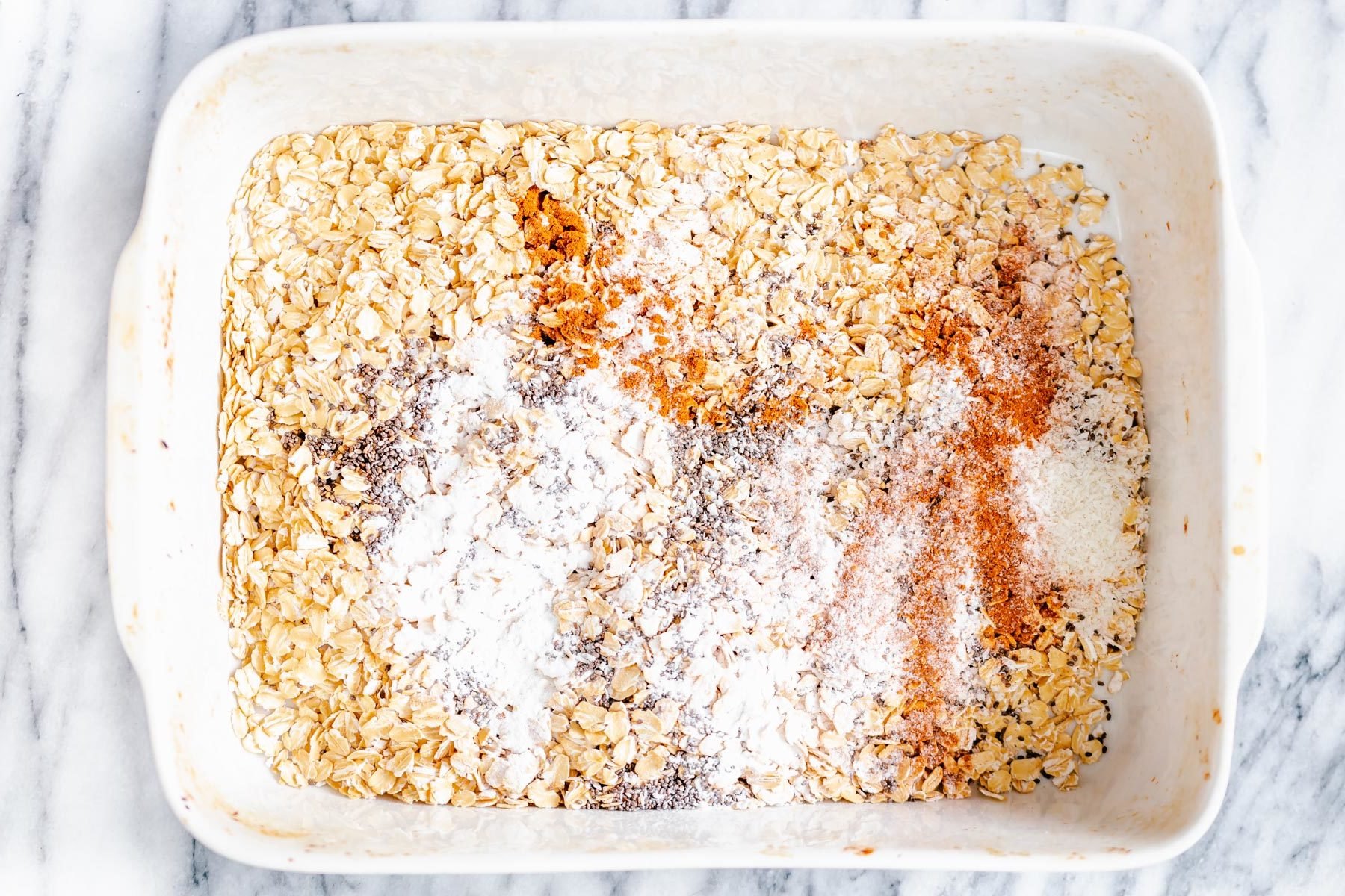 apple pie baked oatmeal ingredients for apple pie baked oatmeal being mixed in a casserole dish