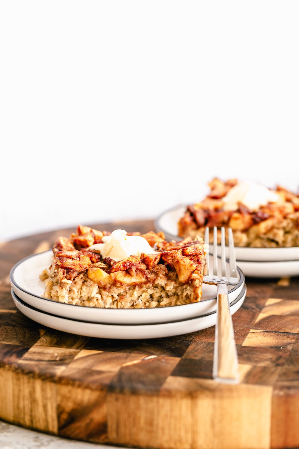apple pie baked oatmeal side view of a serving of vegan apple pie baked oatmeal topped with coconut whip