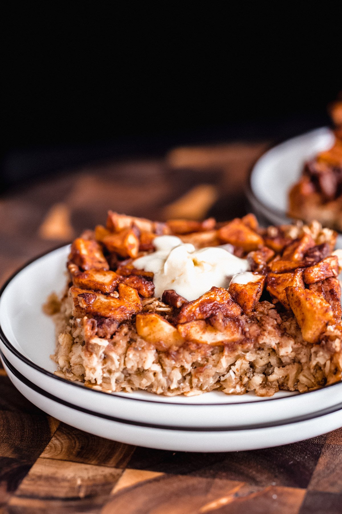 apple pie baked oatmeal close up of a square of apple pie baked oatmeal on a white cake plate