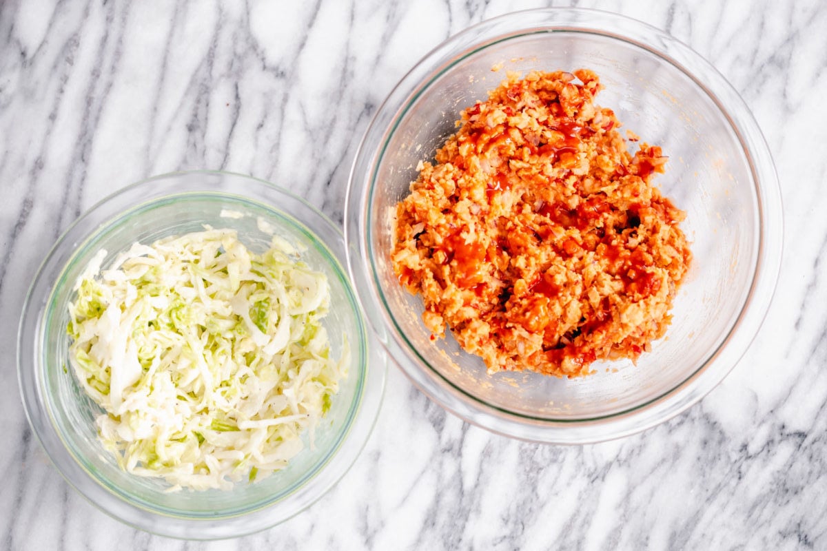 chickpea salad sandwich slaw and buffalo chickpea salad in two glass bowls on a marble countertop