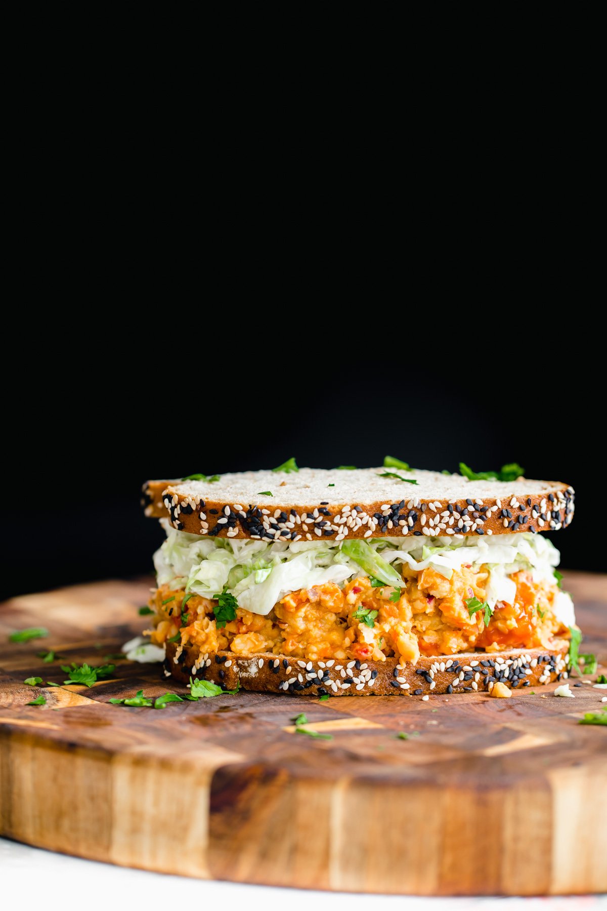 chickpea salad sandwich  side view of vegan buffalo chickpea salad sandwich on a wooden board