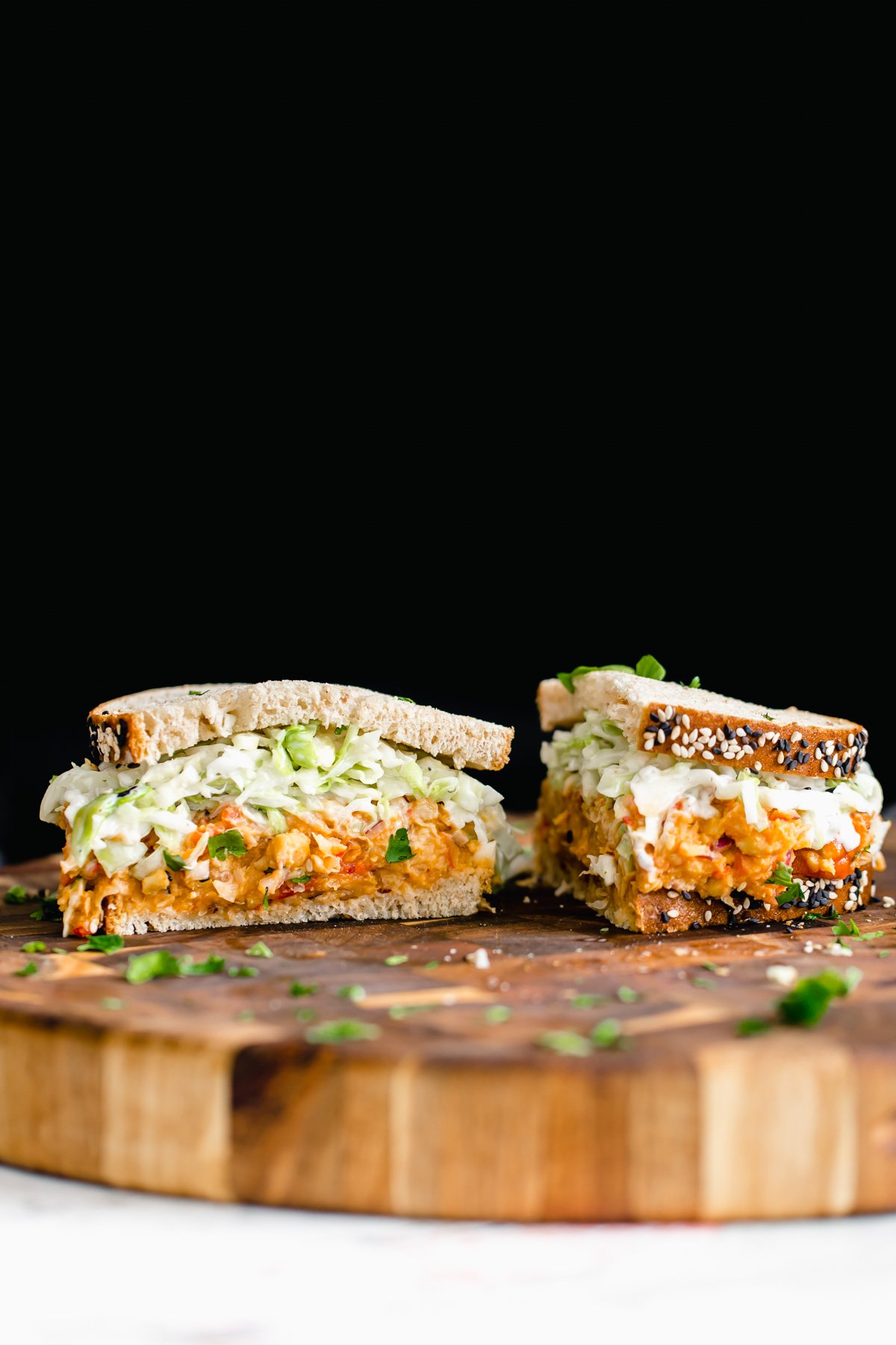 chickpea salad sandwich  a halved chickpea salad sandwich on a wooden board