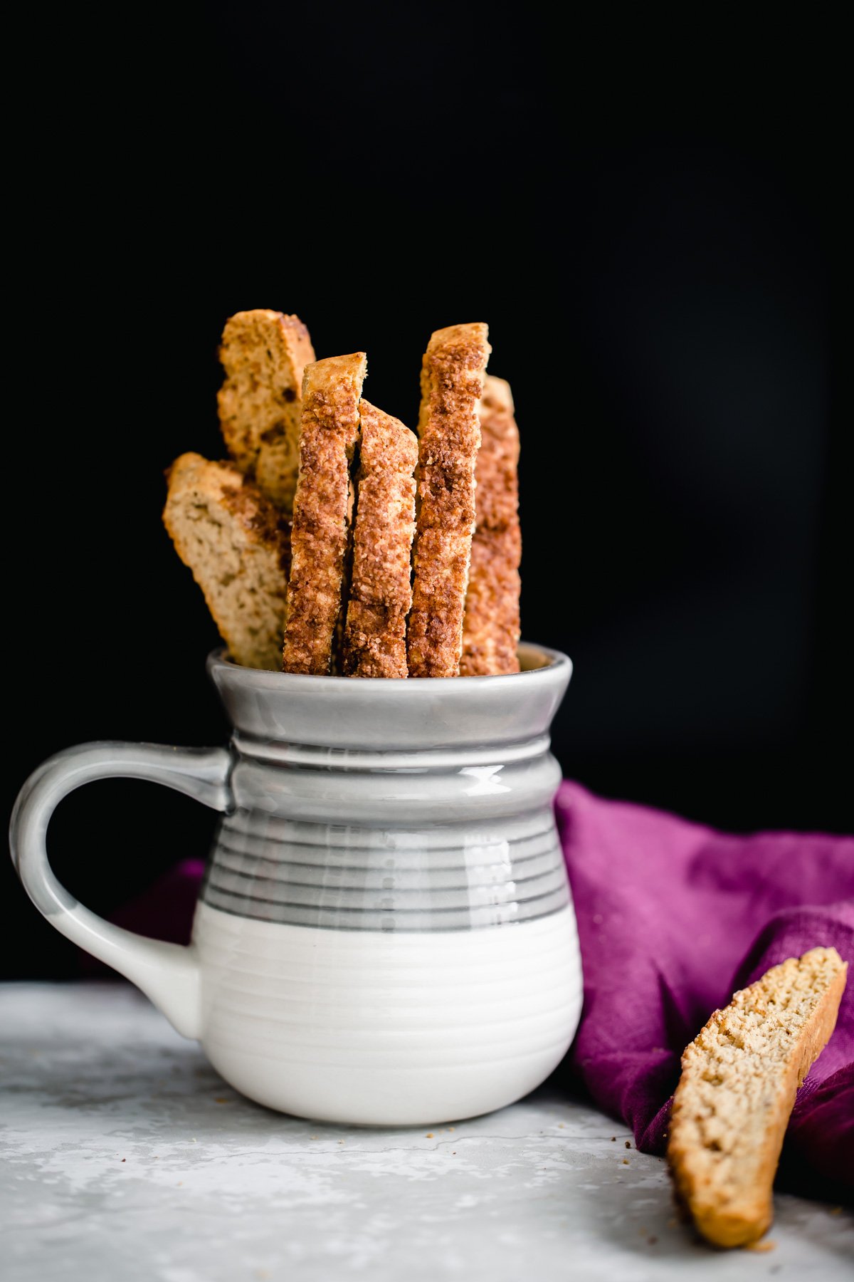 vegan biscotti  homemade vegan churro biscotti peaking out of a grey and white coffee mug