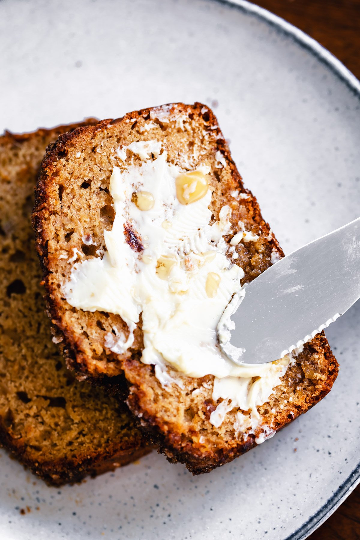 gingerbread banana bread  a slice of vegan gingerbread banana bread being buttered