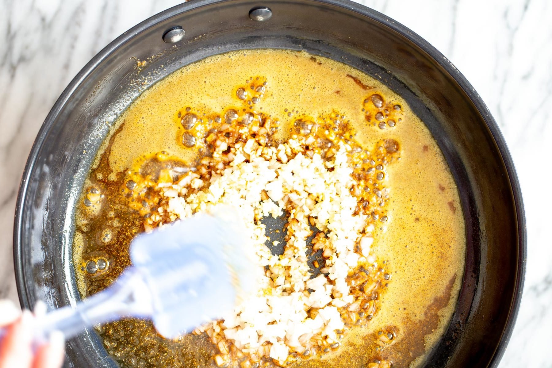 pumpkin curry  overhead shot of a skillet with fried spices and onion as base for curry recipe