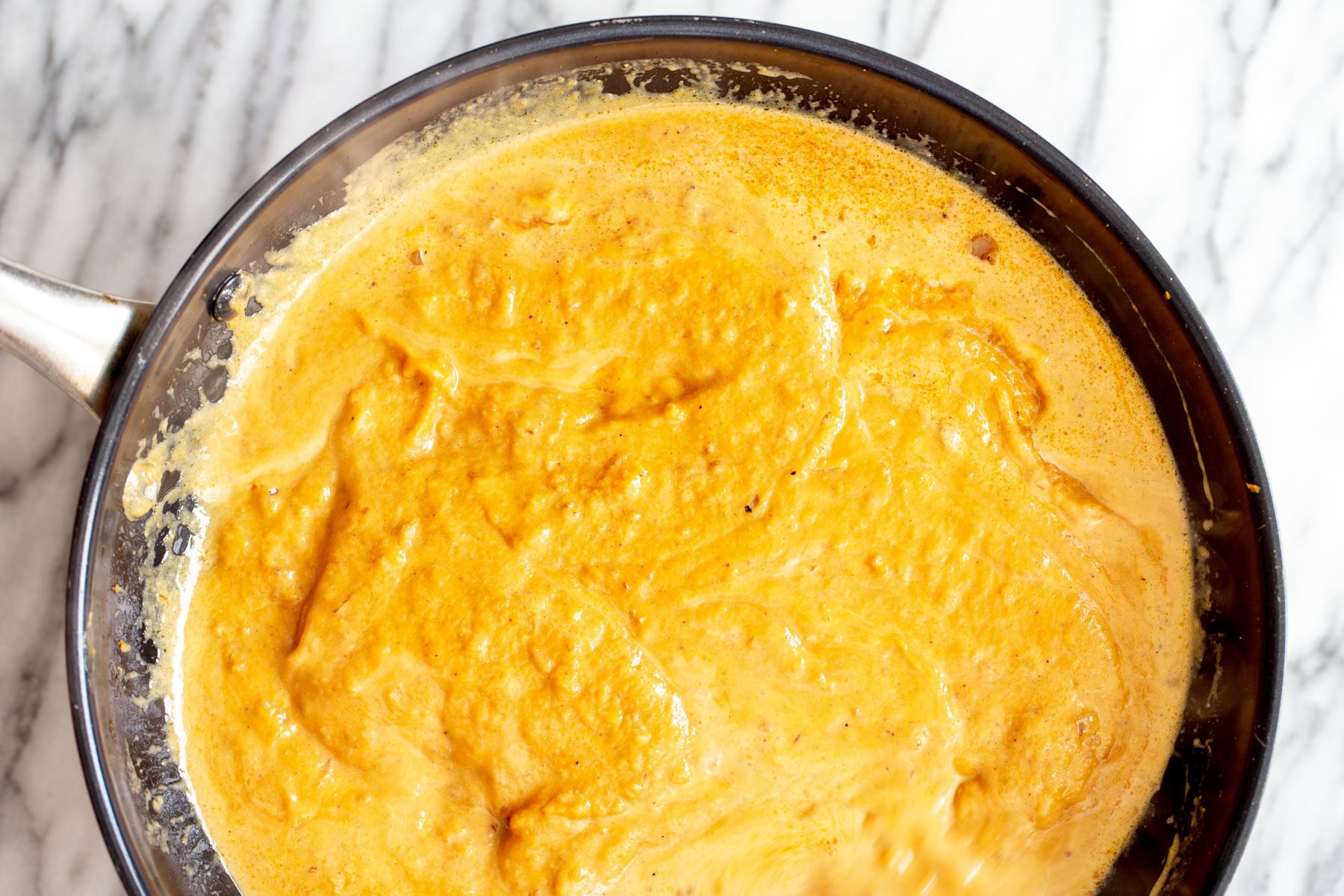 pumpkin curry  overhead shot of a skillet with simmering pumpkin curry