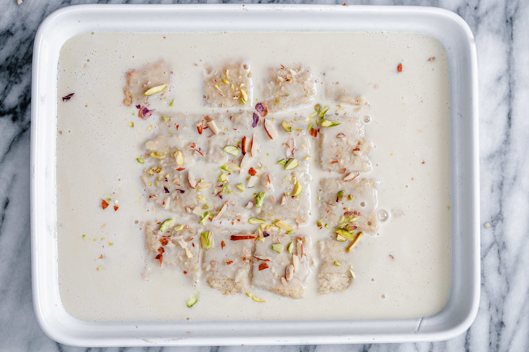 rasmalai cake vegan rasmalai cake being immersed in vegan milk sauce
