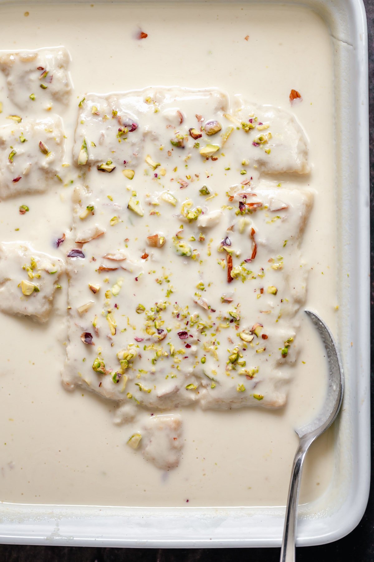 rasmalai cake casserole dish with vegan rasmalai cake with a spoon