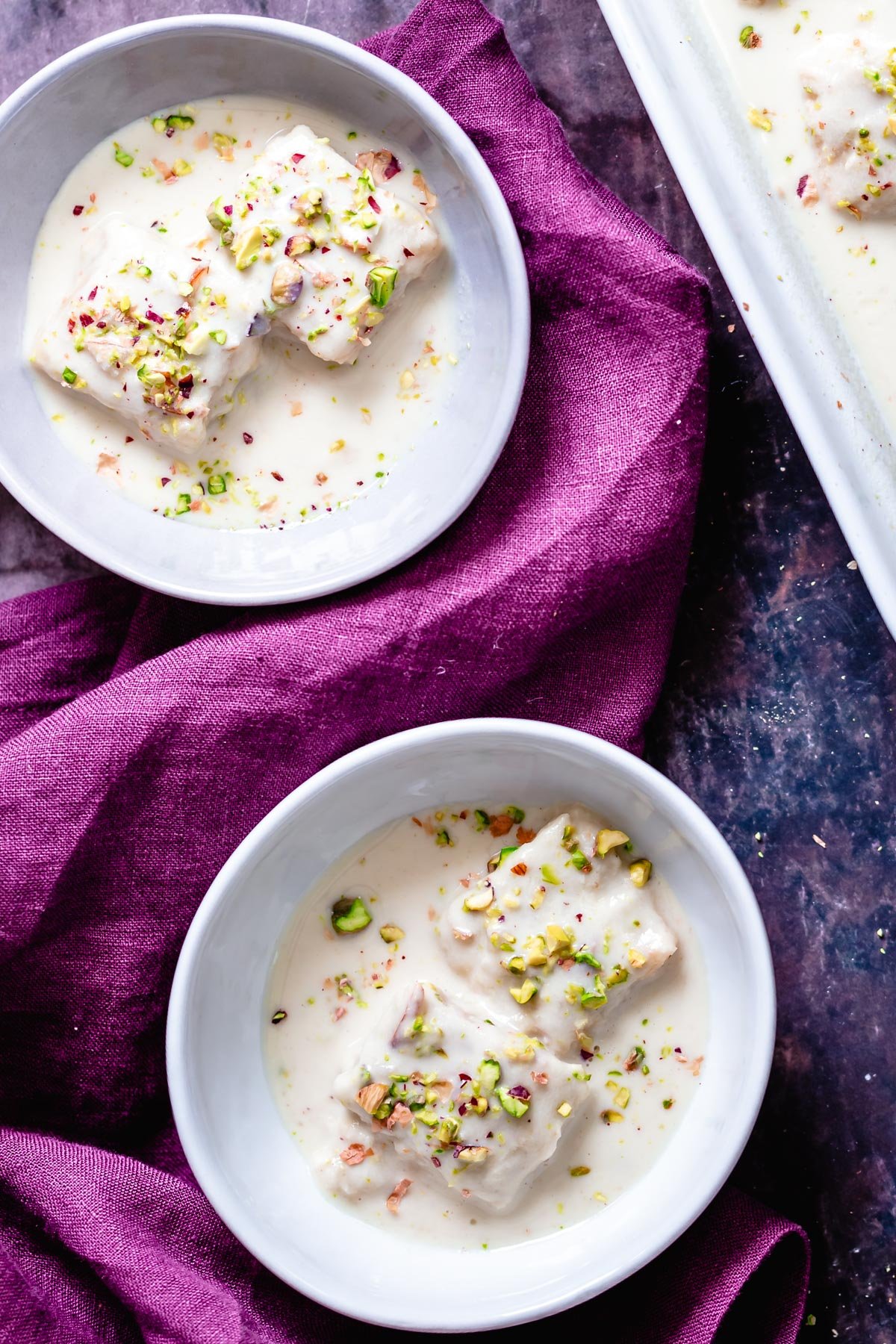 rasmalai cake overhead shot of two bowl of vegan rasmalai cake served with vegan cashew pistachio cream sauce