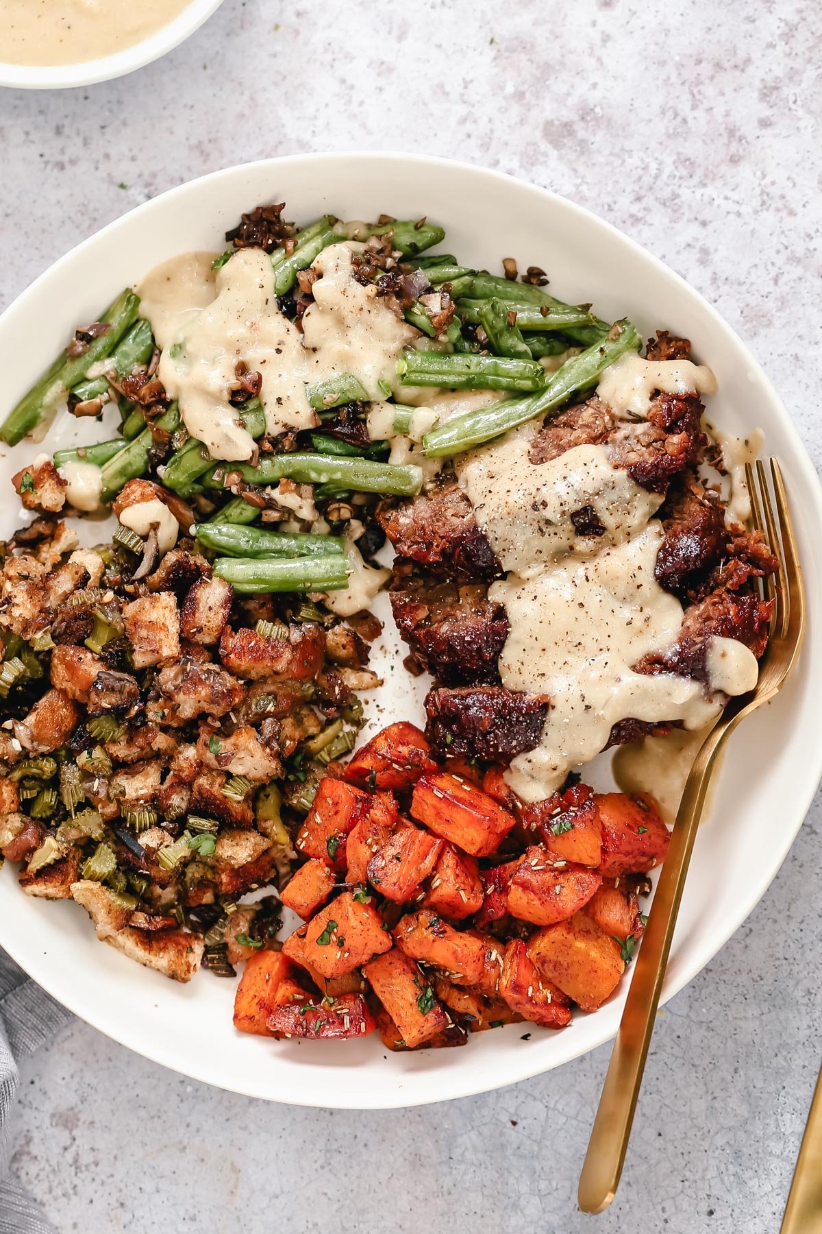 Thanksgiving sheet pan dinner overhead shot of vegan sheet pan Thanksgiving dinner with lentil loaf and three sides all served in a plate