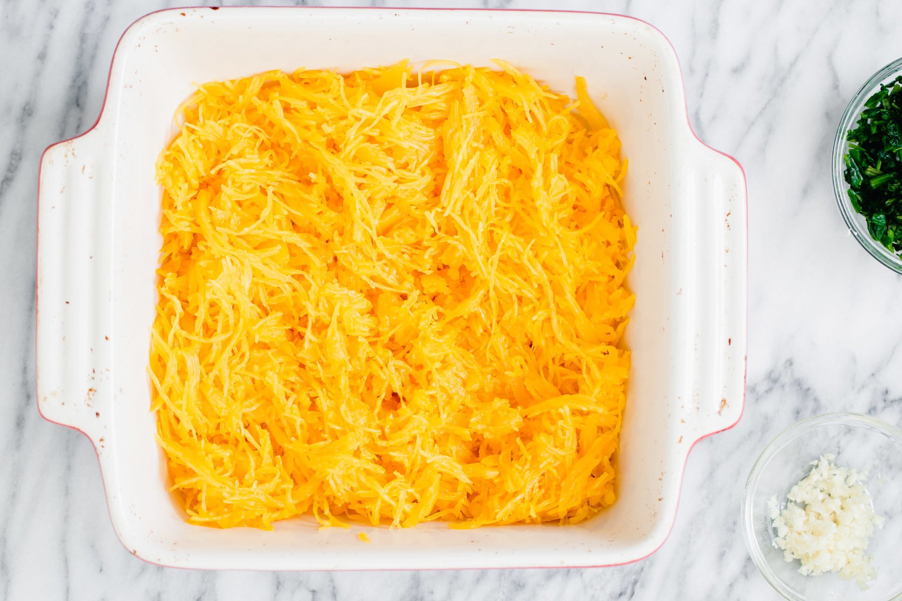 spaghetti squash bake  cooked spaghetti squash noodles in a white casserole dish