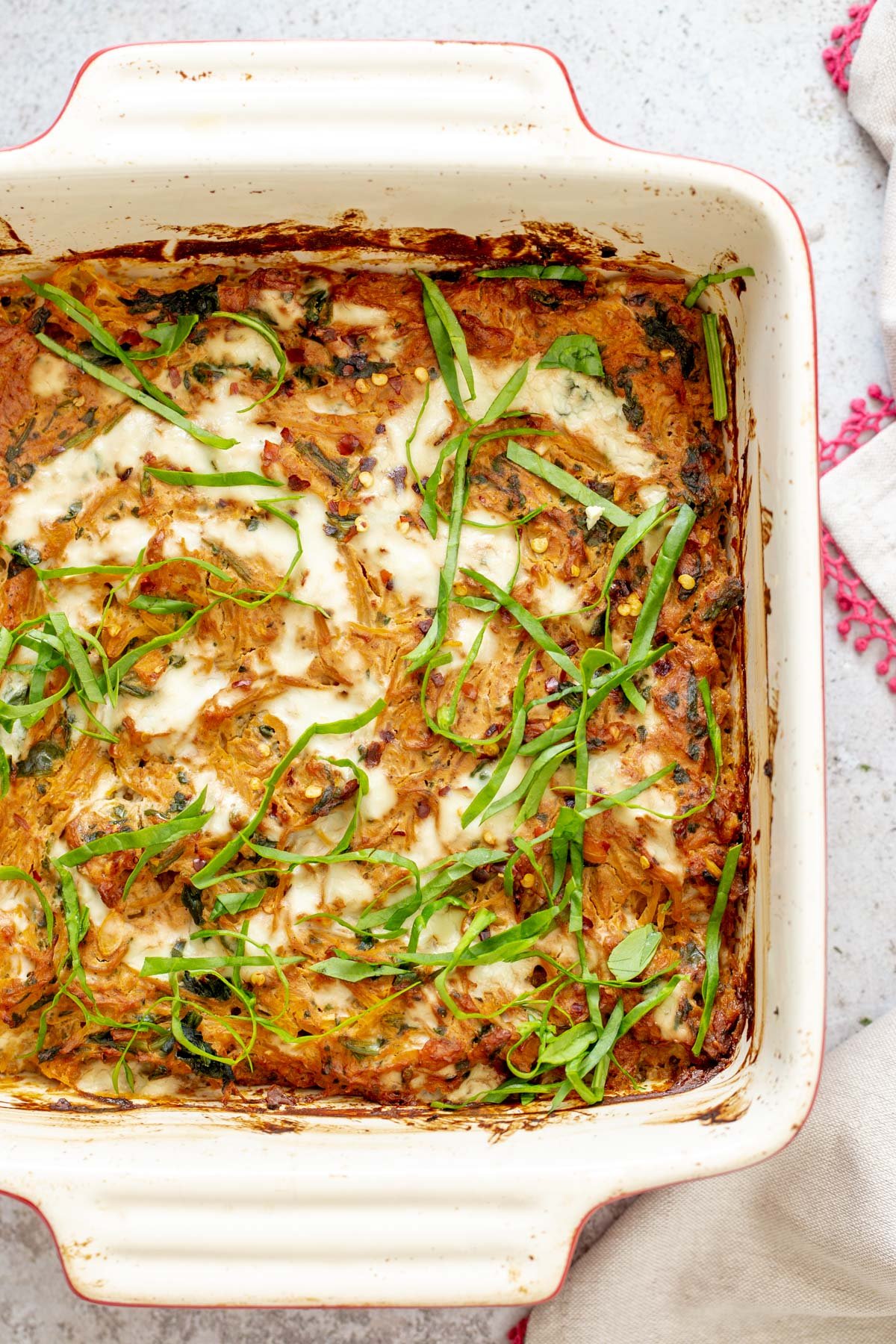 spaghetti squash bake  overhead shot of a casserole dish with vegan spaghetti squash bake sprinkled with fresh chopped basil