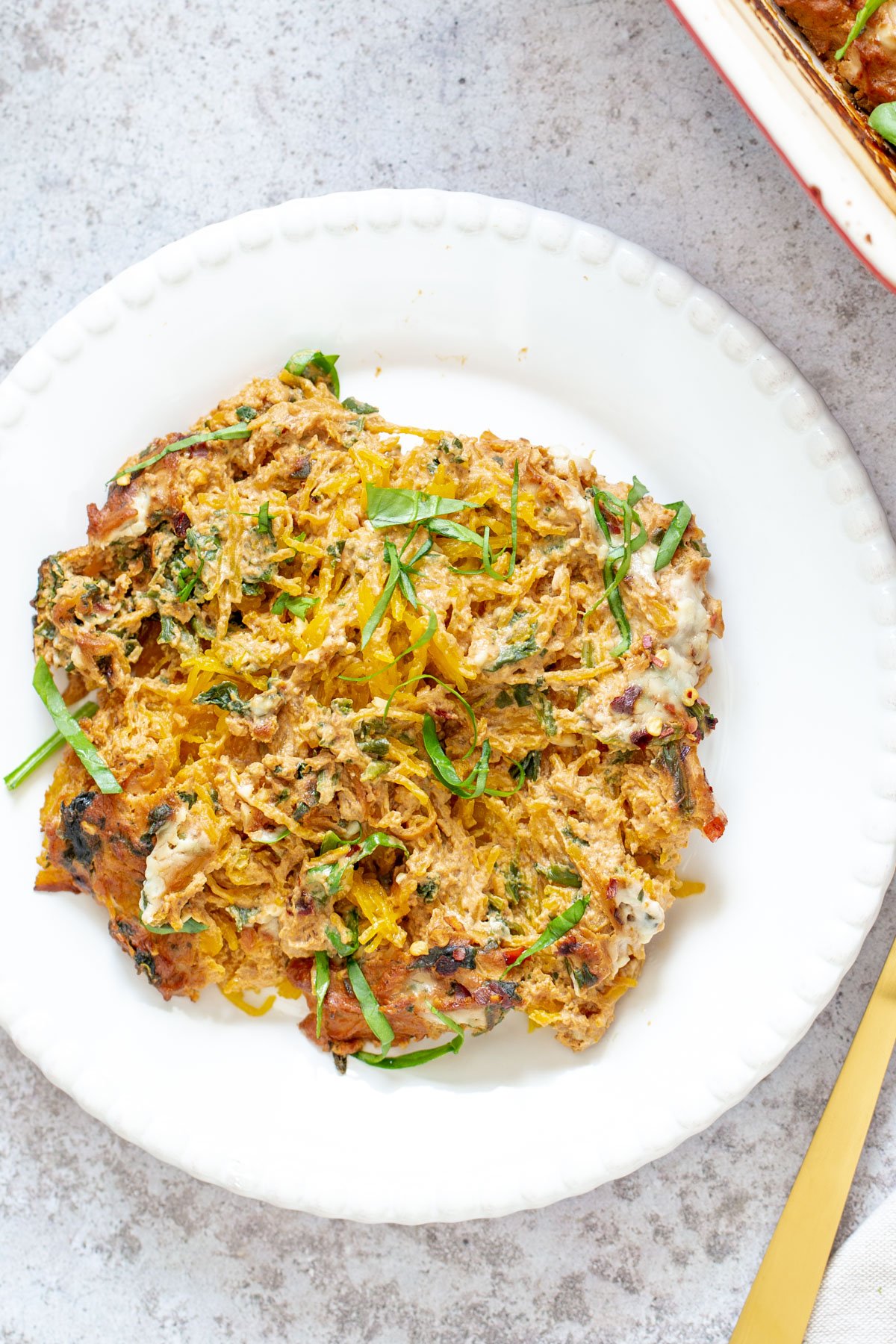 spaghetti squash bake  a serving of vegan spaghetti squash pasta bake on a white plate with a golden fork