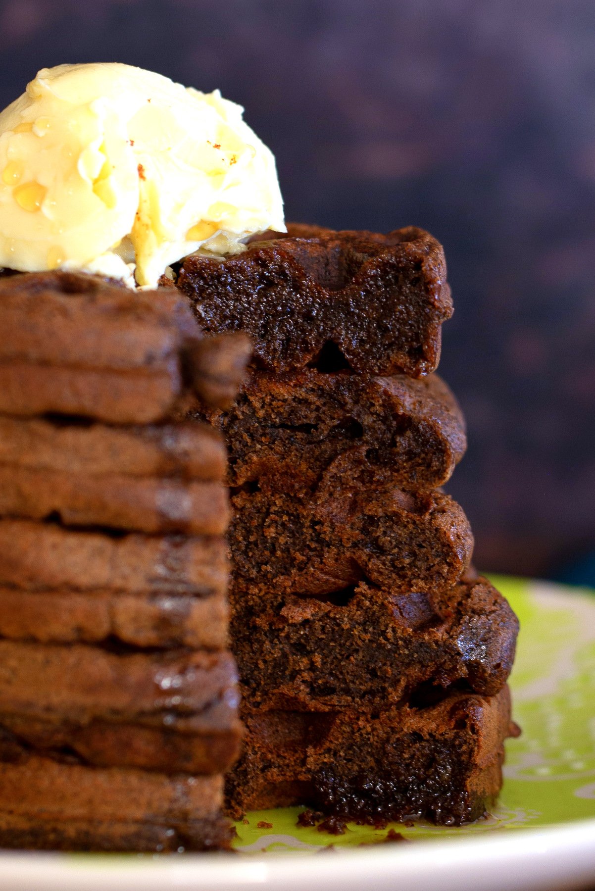 side view of a stack of chocolate buckwheat waffles topped with vegan butter