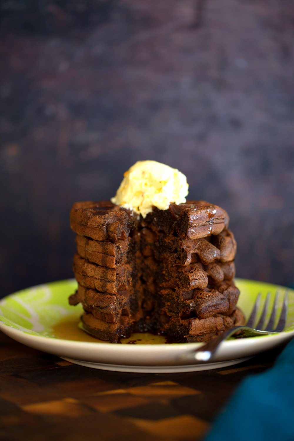 a stack of buckwheat waffles topped with vanilla ice cream with a corner cut out