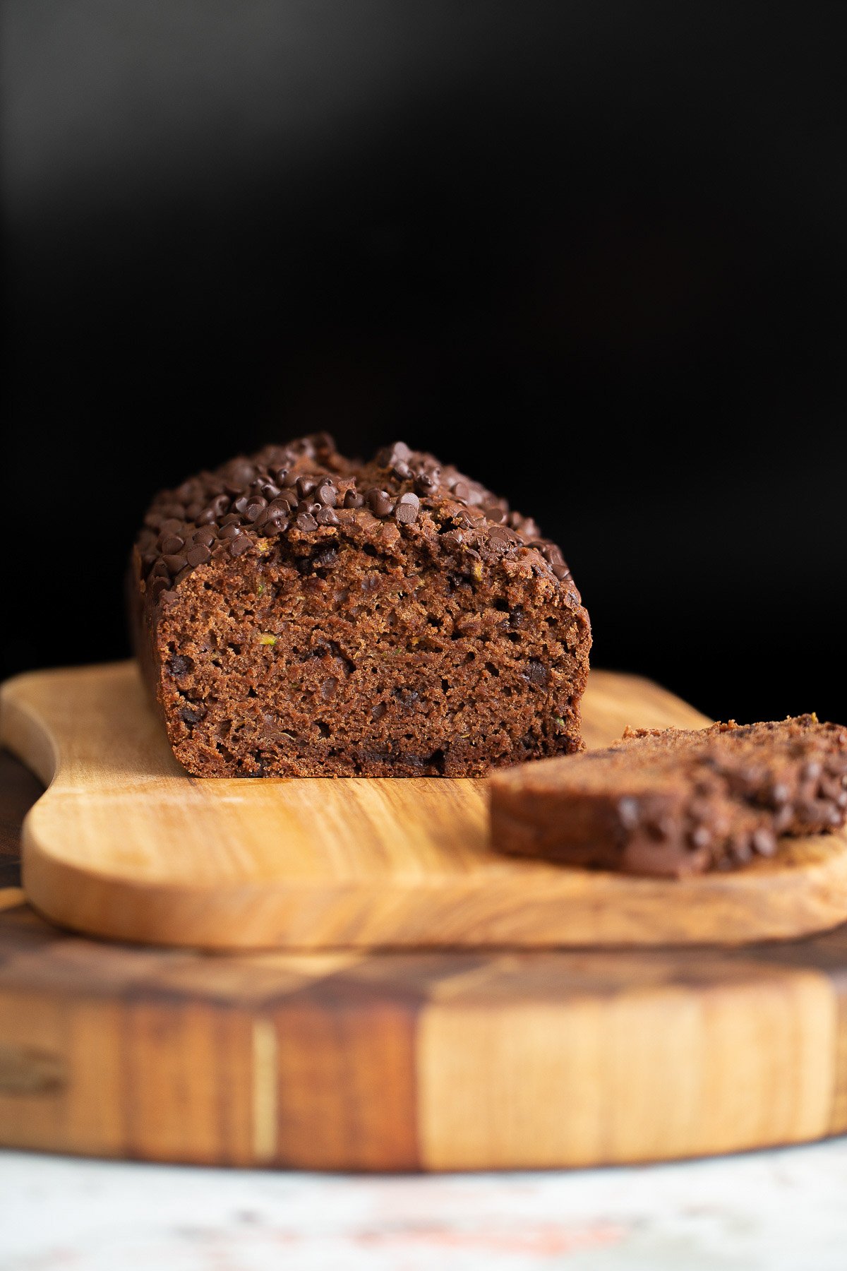 chocolate zucchini bread  a sliced loaf of chocolate zucchini bread on a wooden chopping board