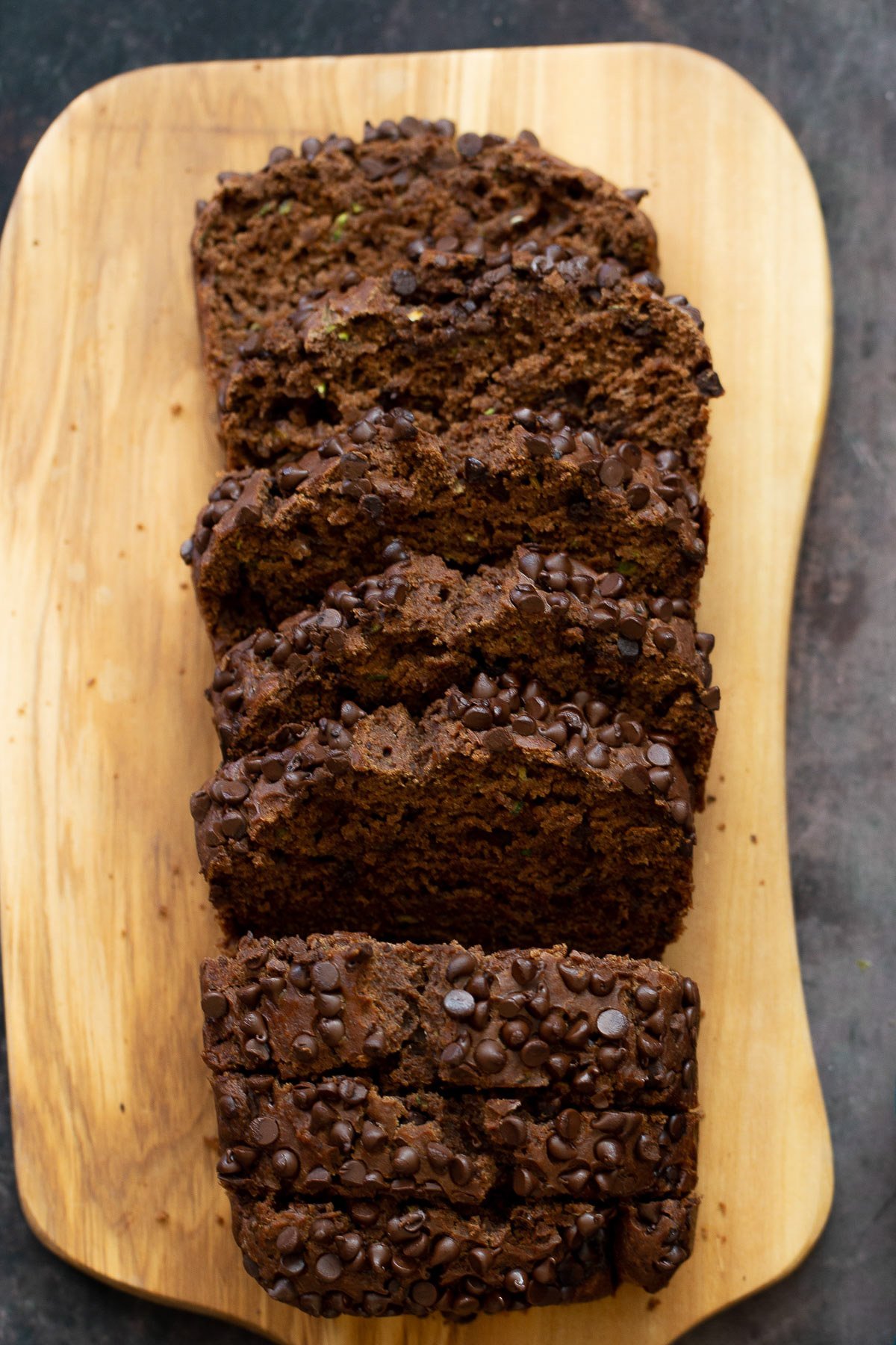 chocolate zucchini bread  overhead shot of a sliced loaf of vegan chocolate zucchini bread on a wooden chopping board