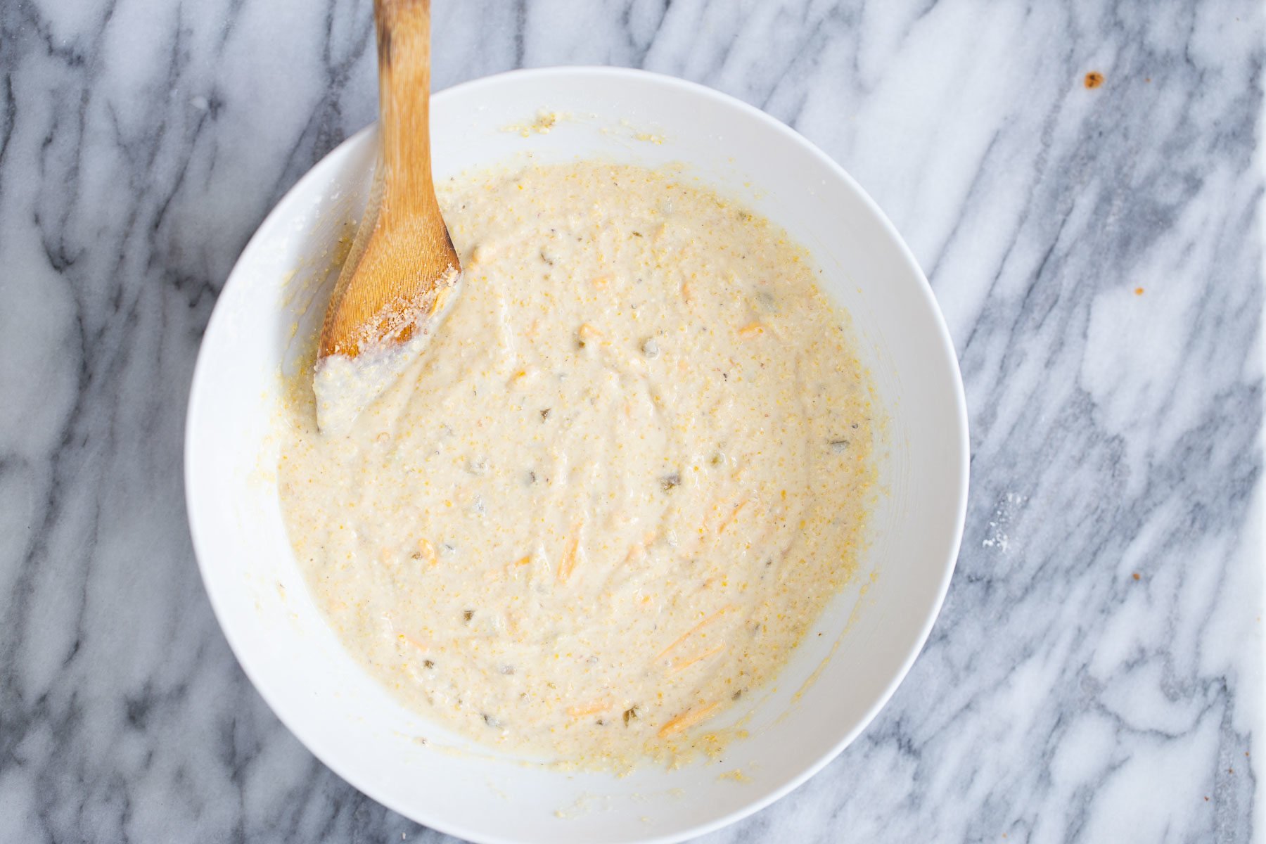 chili cornbread casserole cornbread batter with pieces of jalapeno and cheddar shreds