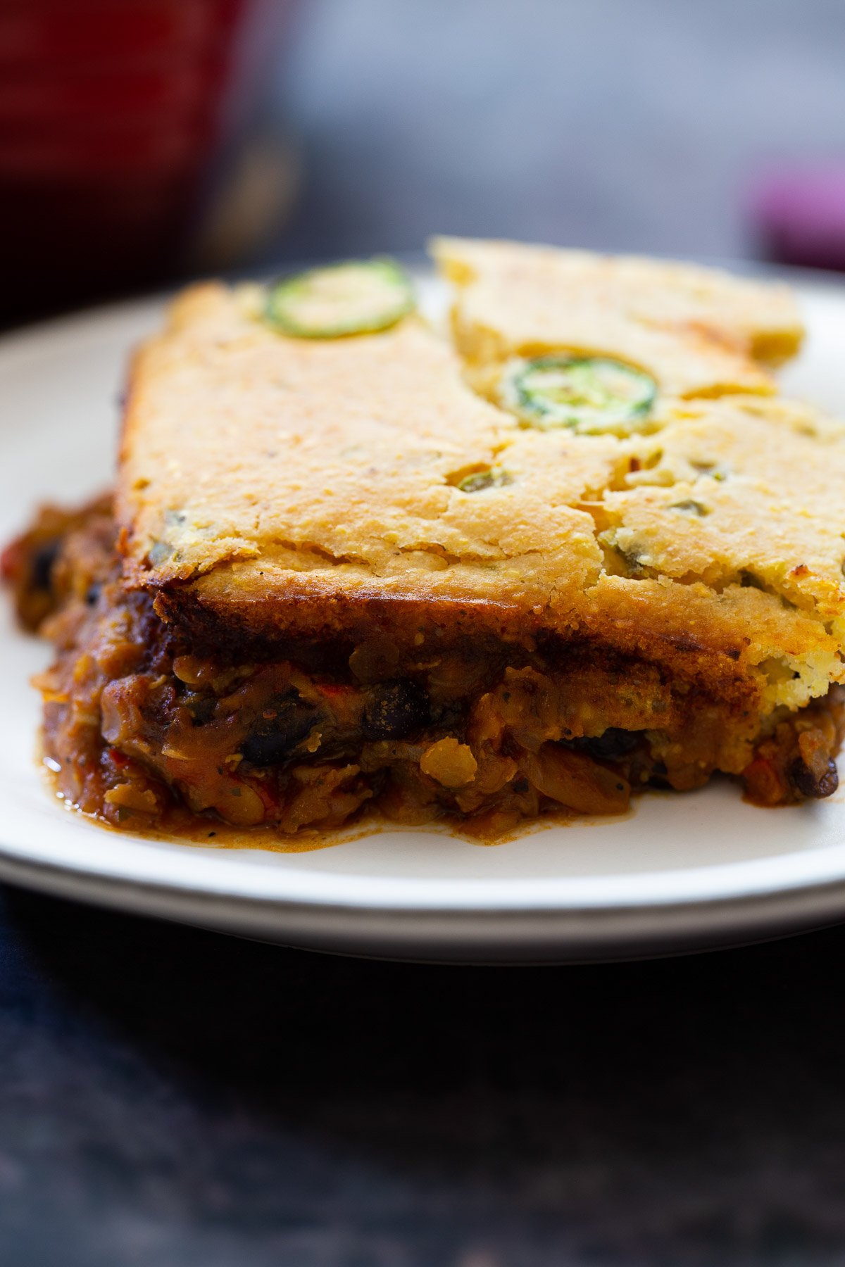 chili cornbread casserole side view of a square of chili cornbread casserole on a white plate