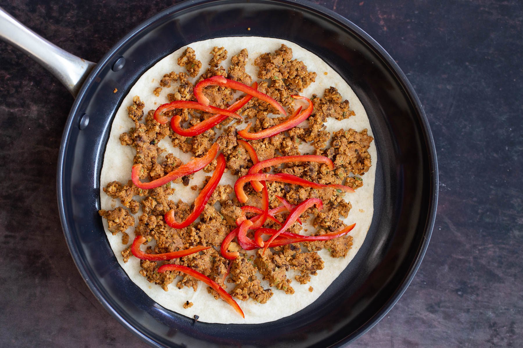 walnut taco meat vegan walnut taco meat quesadilla being assembled in black skillet
