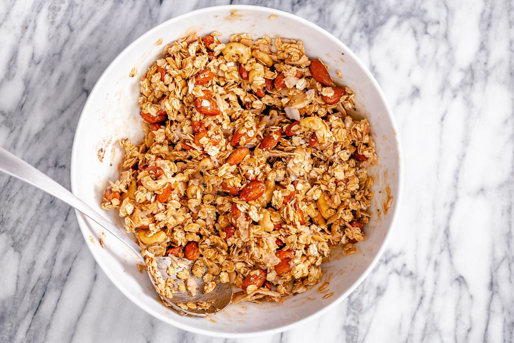 coconut granola  almond coconut granola being mixed in a small white bowl
