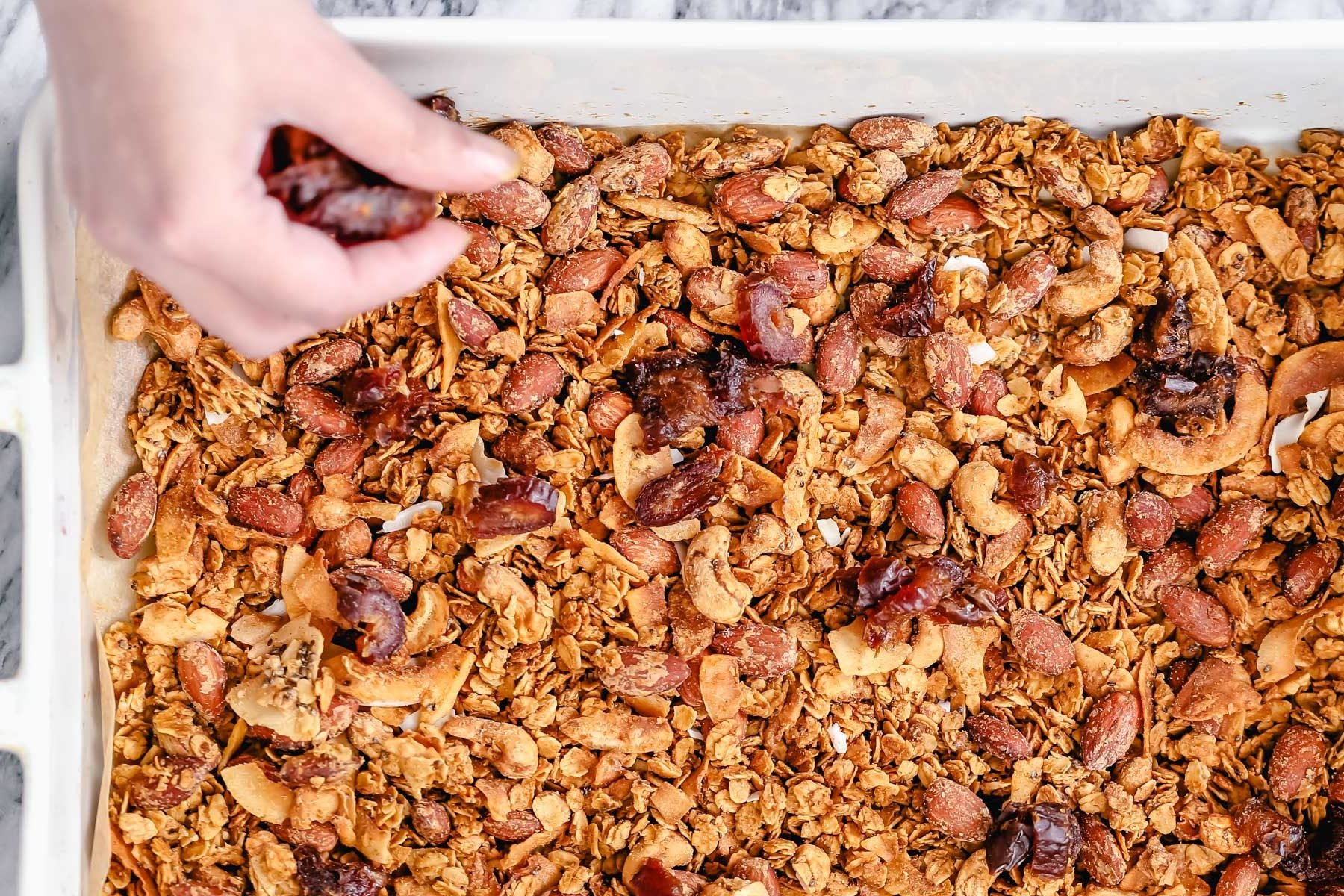 coconut granola  baked vegan granola being spread out in a casserole dish
