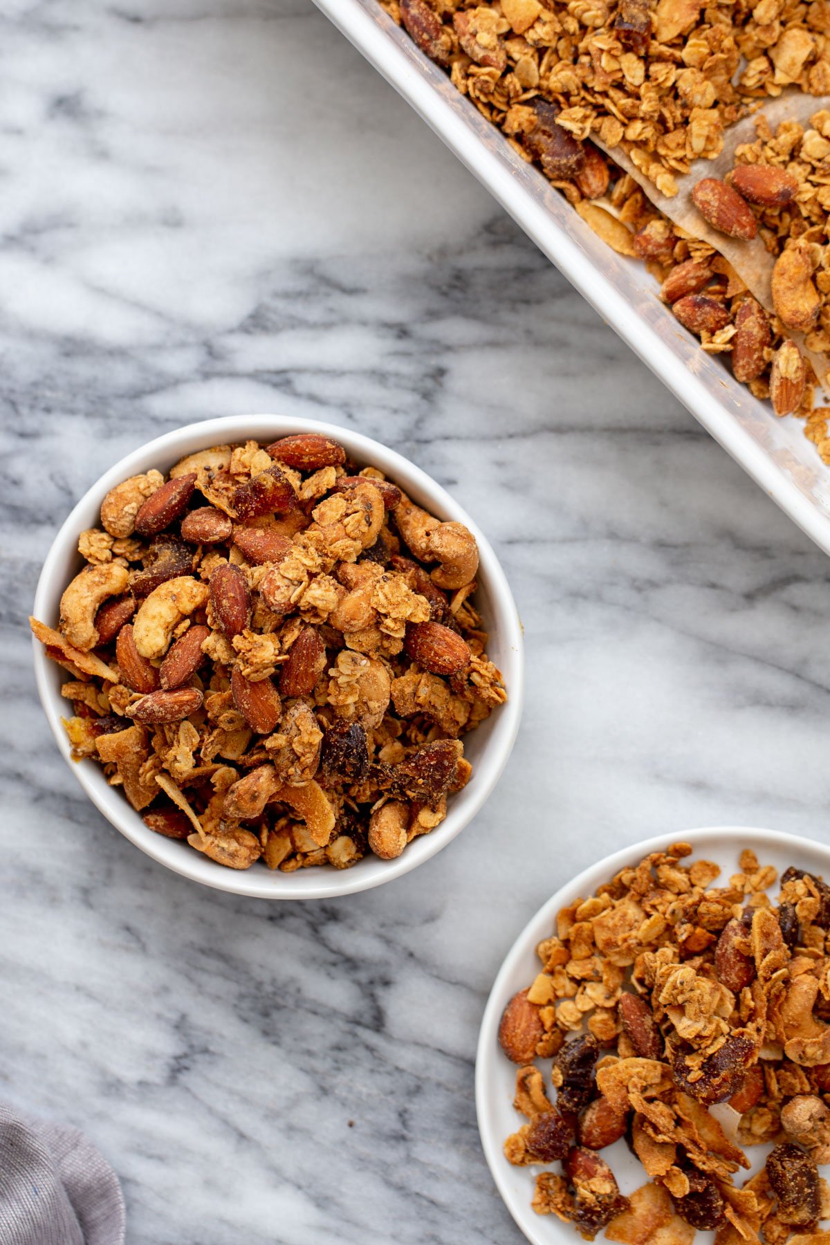 coconut granola two small bowls of vegan almond coconut granola on a marble countertop