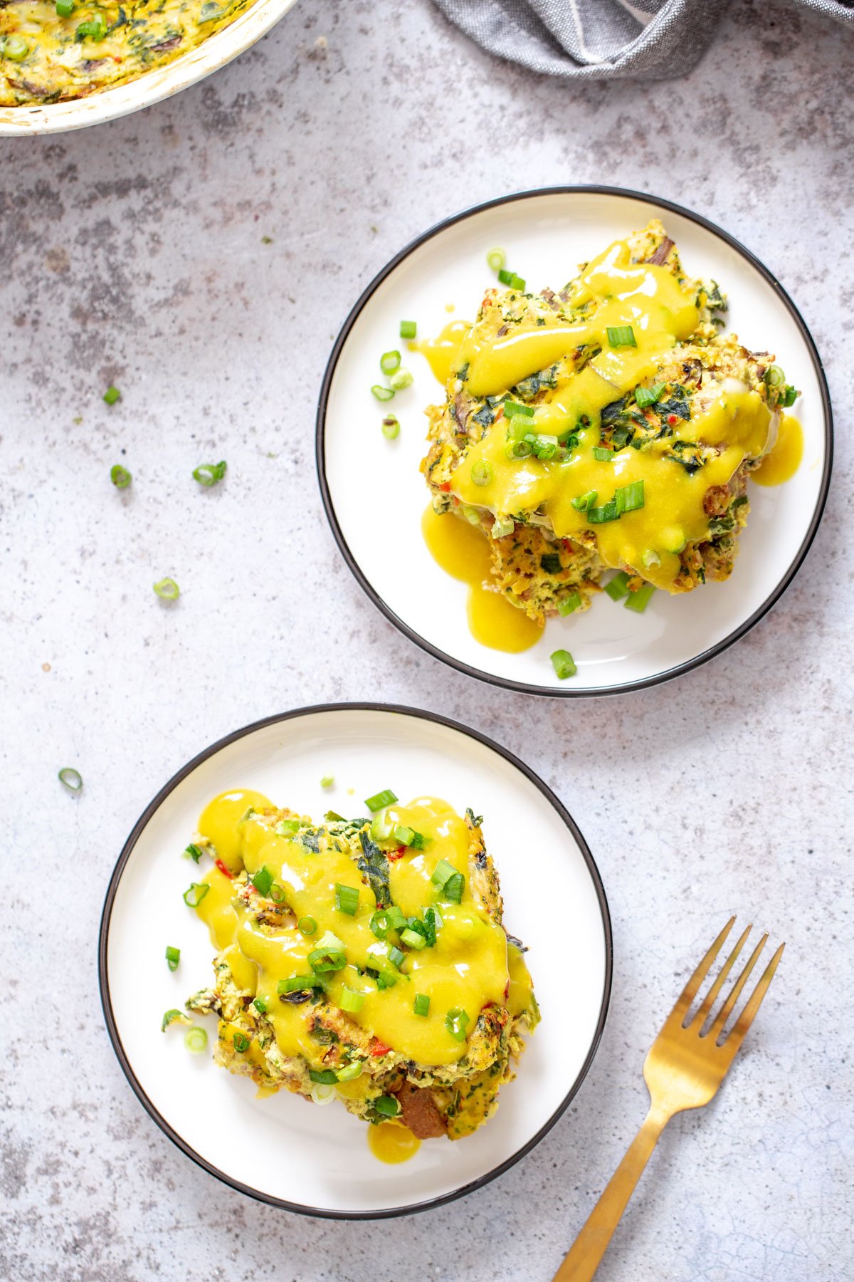 vegan breakfast casserole overhead shot of two servings of vegan egg breakfast casserole with vegan hollandaise