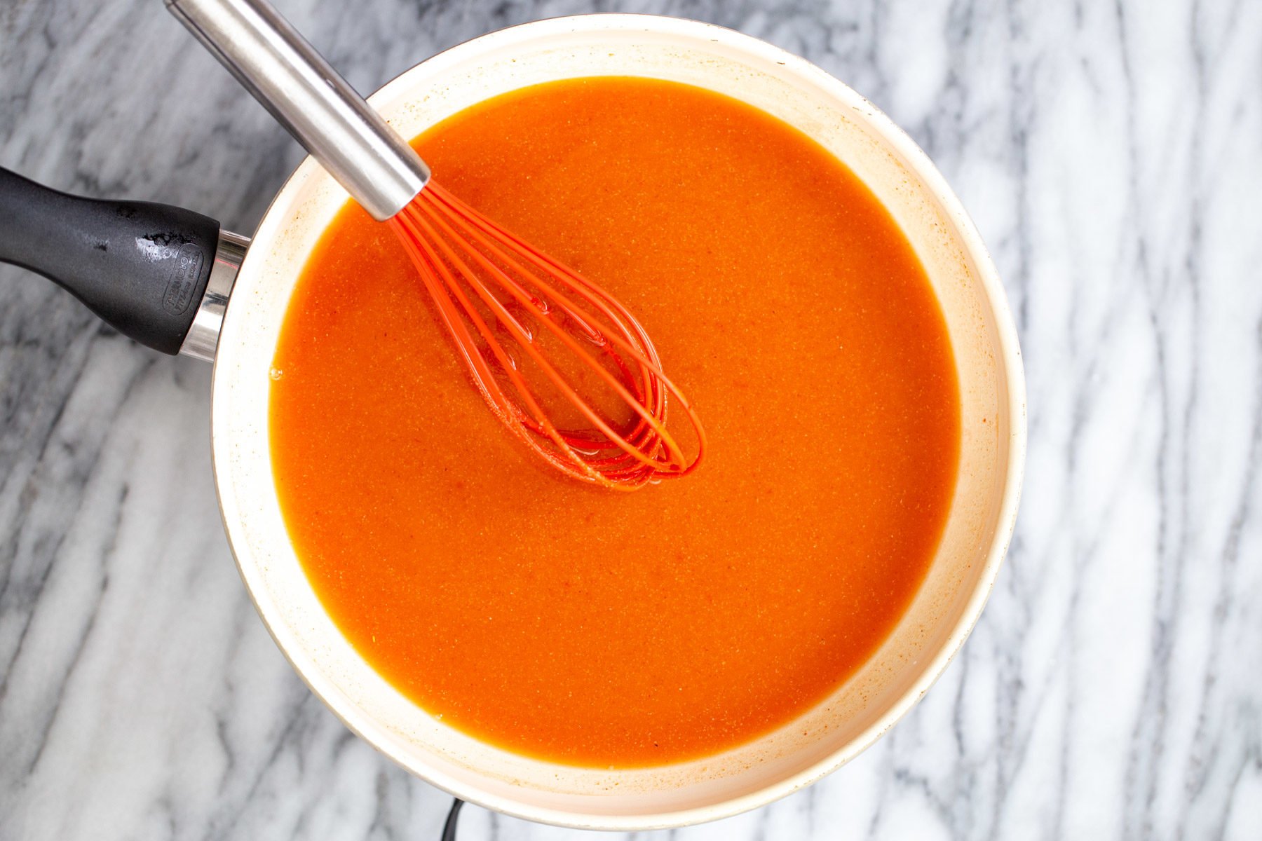 tofu wings  firecracker sauce being stirred together in a white saucepan