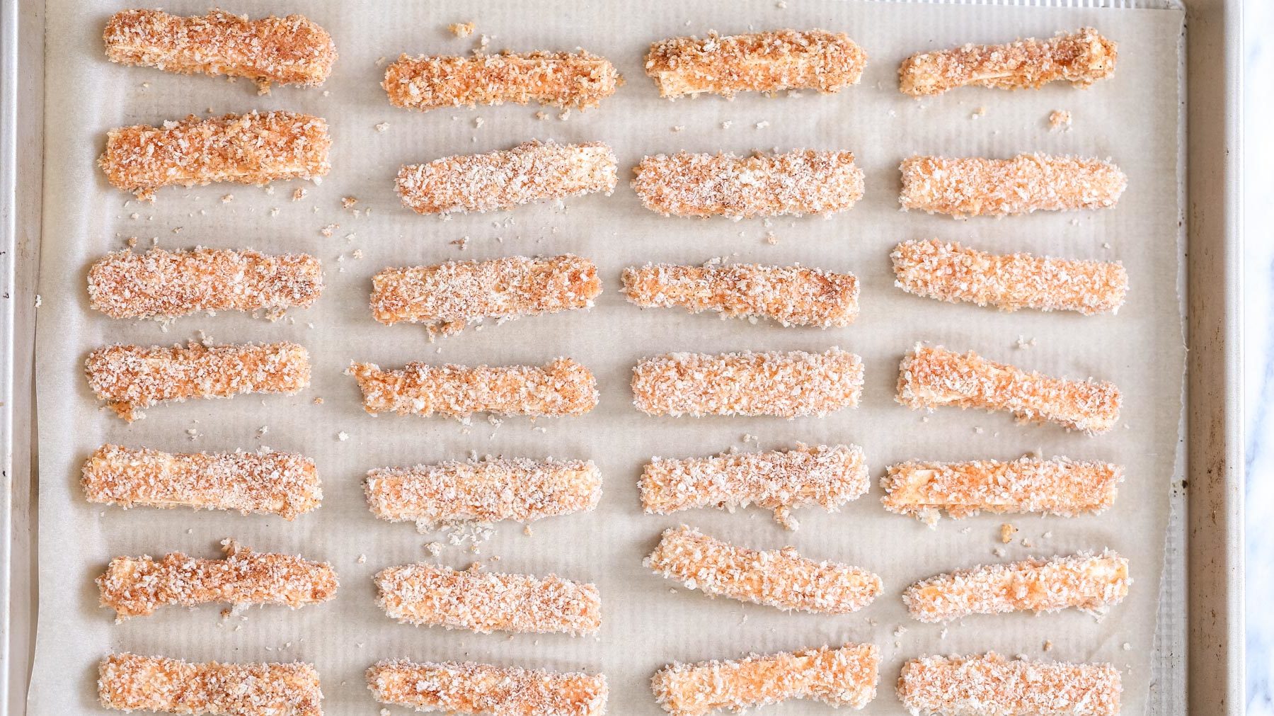 tofu wings  breaded vegan tofu wings on.a parchment paper lined baking sheet