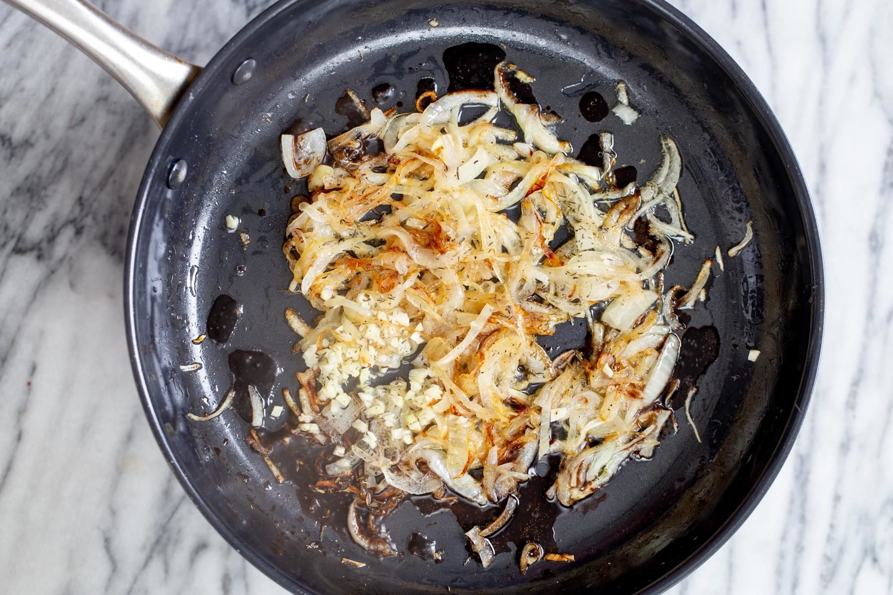 Vegan Skillet Lasagna  garlic being added to caramelized onion slices in a skillet