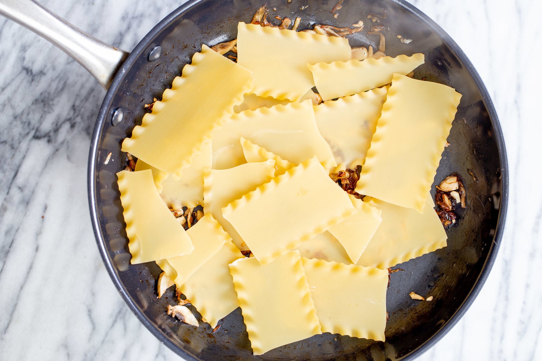 vegan skillet lasagna lasagna noodles being added to a skillet to make skillet lasagna