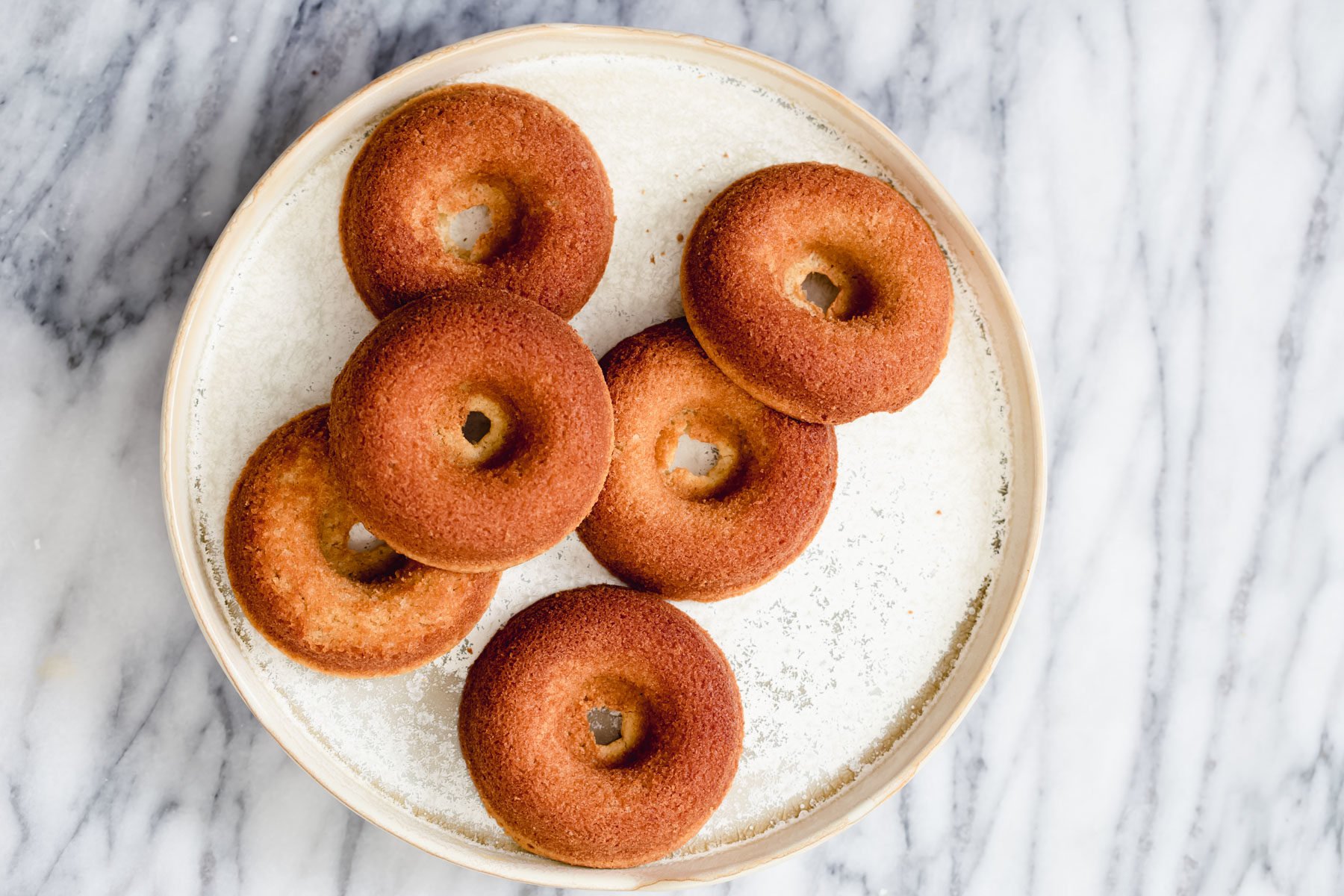 glutenfree donuts recipe overhead shot of a white plate with glutenfree donuts on a marble kitchen table