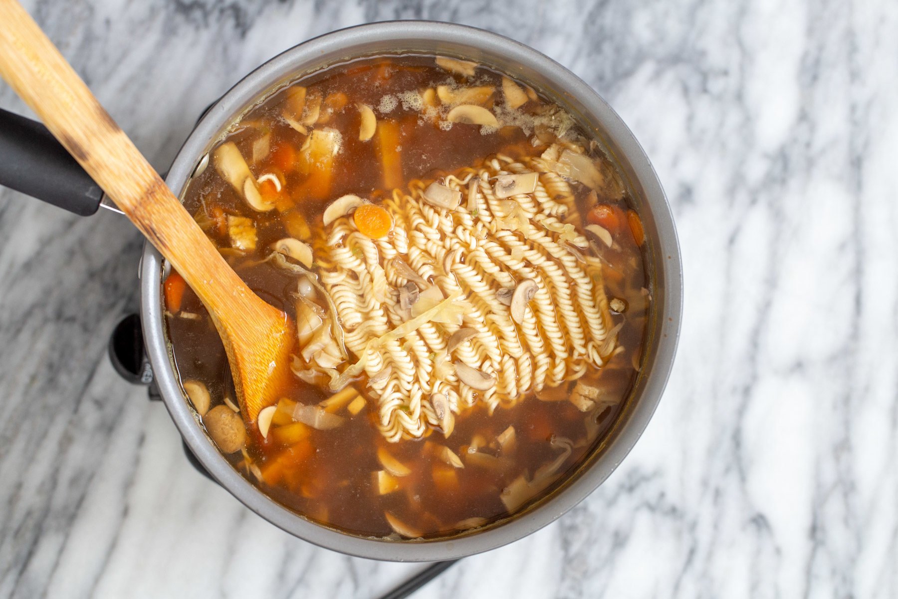 vegan hot and sour soup  ramen noodles being added to a pot of vegan hot and sour ramen soup
