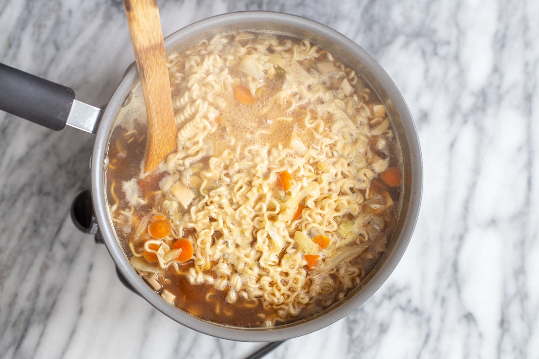ramen noodles being cooked in hot and sour broth to make vegan Chinese soup