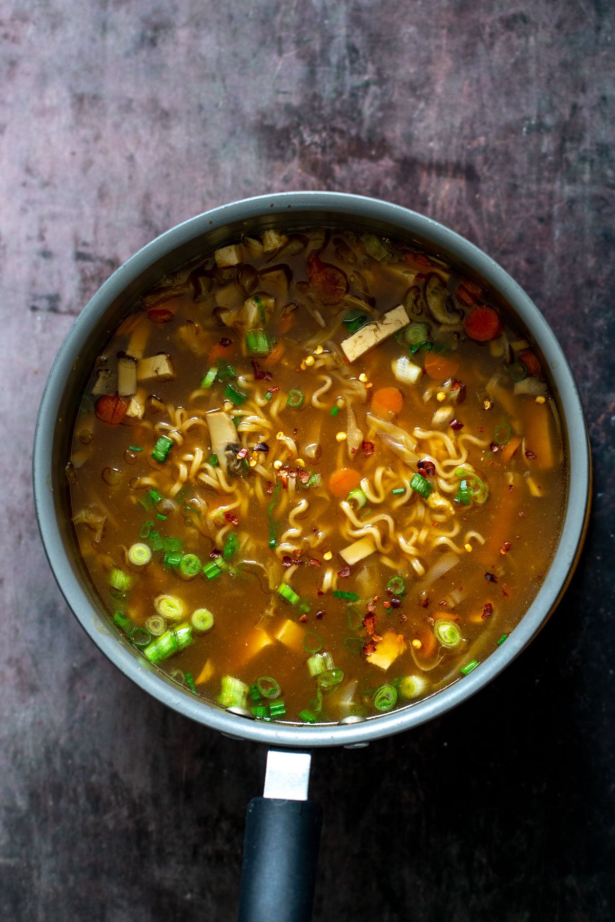 overhead shot of a pot of vegan hot and sour soup with ramen noodles and mushrooms